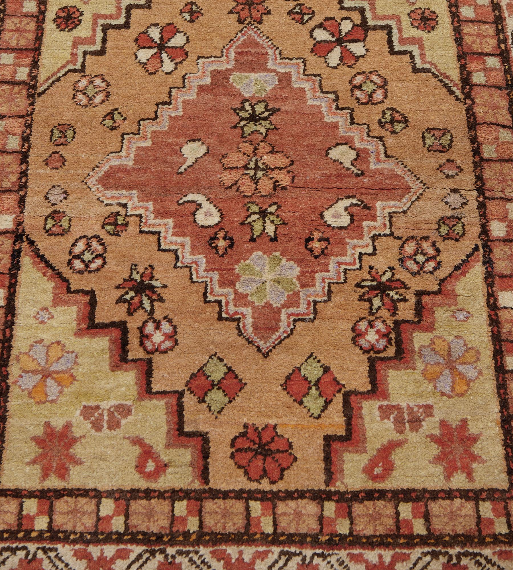 Cette ancienne coulisse Khotan, vers 1900, présente un champ de losanges en escalier et reliés en terre cuite douce, chacun avec de délicats motifs floraux autour d'un losange central en escalier rouge renard et lilas avec des motifs floraux et de