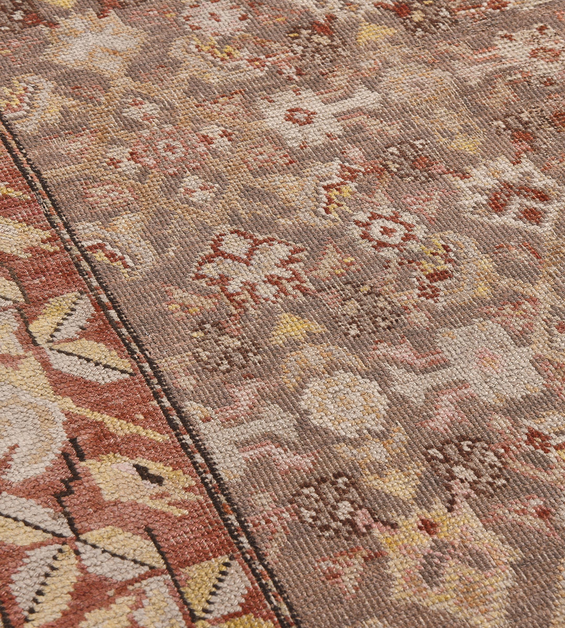 Dieser traditionelle, handgewebte Karabagh-Teppich hat ein staubiges, pistaziengraues Feld mit einem polychromen Herati-Feld in einer rostfarbenen, stilisierten, geometrischen Blumenrankenbordüre, die von schmalen, geometrischen Streifen eingefasst