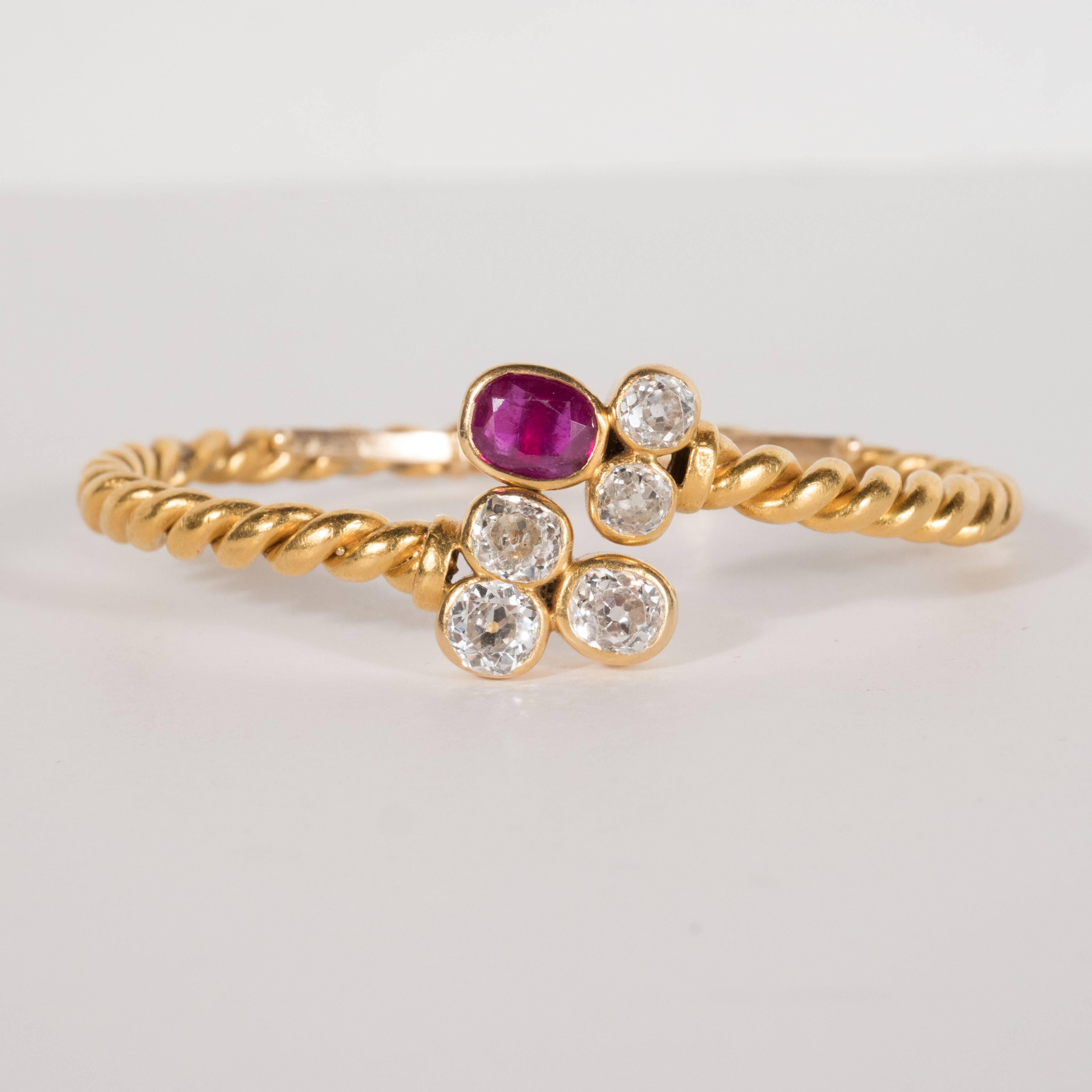 This exquisite hand wrought bangle bracelet was realized in America, circa 1925. It features 2.5kt of fine Old European Cut Diamonds as well as a large 24kt oval ruby set in 18kt gold. The bracelet features a hand wrought braided twisted rope