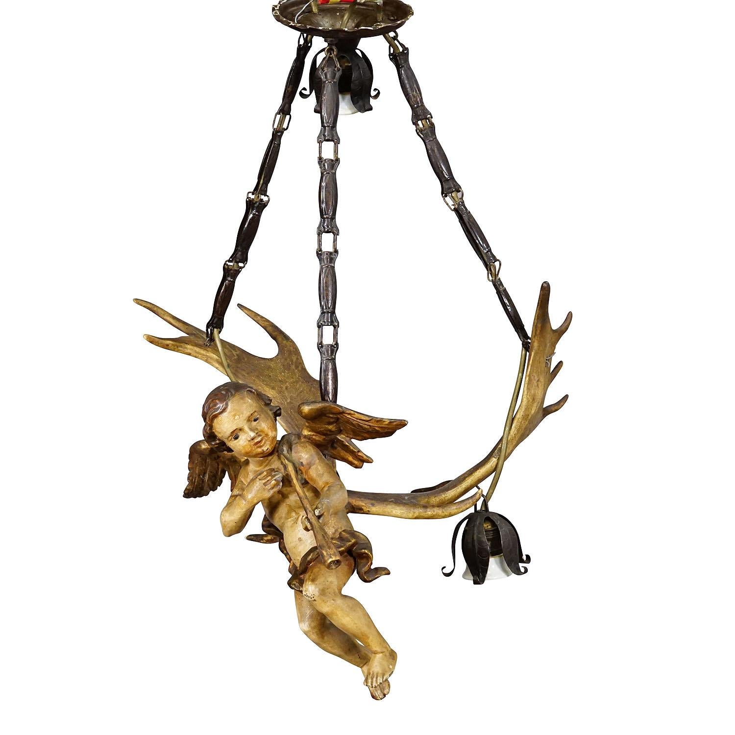 Antique Handcarved Lusterweibchen of an Angel ca. 1900

A lovely antique lusterweibchen chandelier depicting a fanfare playing angel. The sculpture is made of wood with handpainted finish and mounted on a pair of fallow deer antlers. It features a