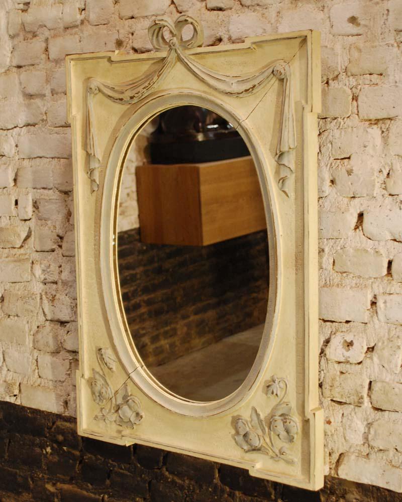 A handsome mirror, hand carved from solid oakwood and painted in natural colors.
The mirror has a rectangular shape with an oval mirror. It is adorned with a bow tied ribbon ending in draped curtains. Typical Art Nouveau floral elements were carved