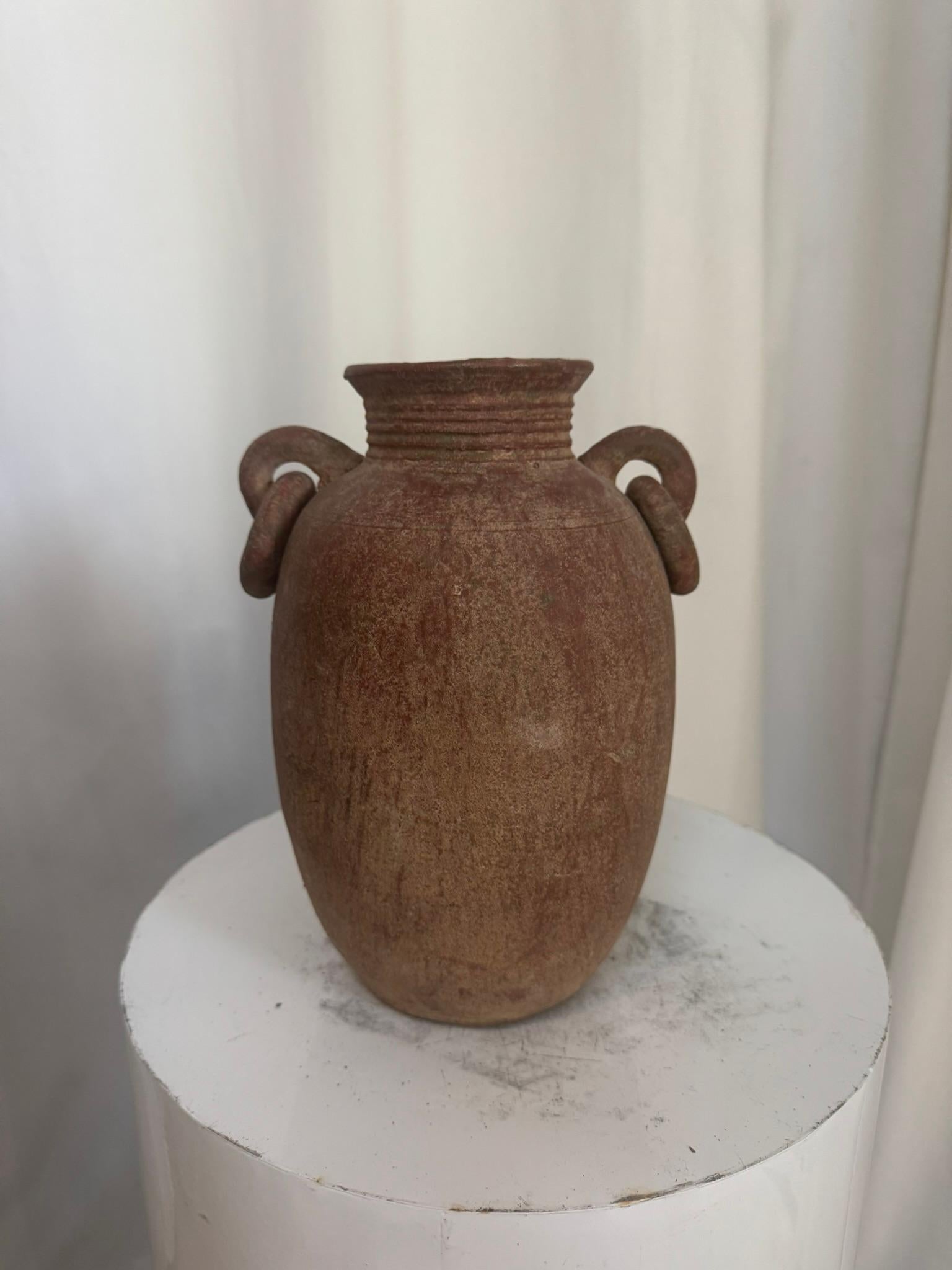 Questa straordinaria anfora antica incarna l'arte duratura della ceramica tradizionale, offrendo non solo un recipiente, ma un legame tangibile con i ritmi della vita antica. Modellata a mano in terracotta naturale, presenta una patina