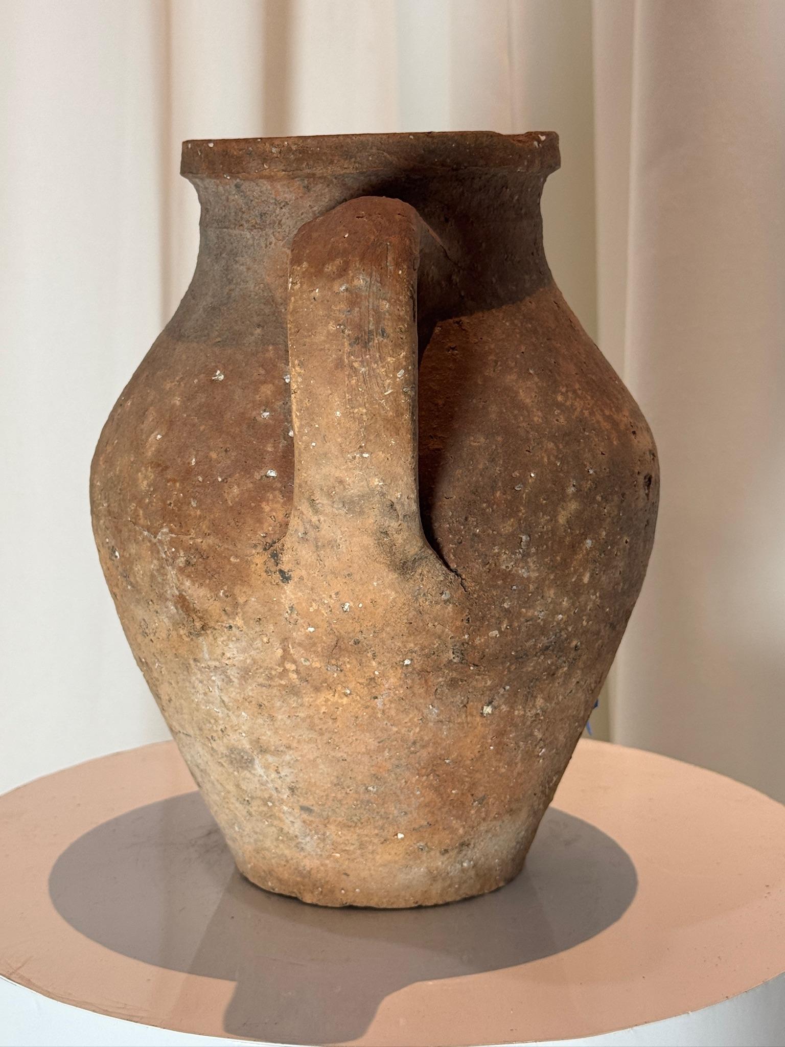 Questo antico vaso di terracotta lavorato a mano è un esempio straordinario di ceramica tradizionale, caratterizzato da una patina splendidamente invecchiata e da un fascino rustico e senza tempo. Probabilmente originario dell'Europa o del