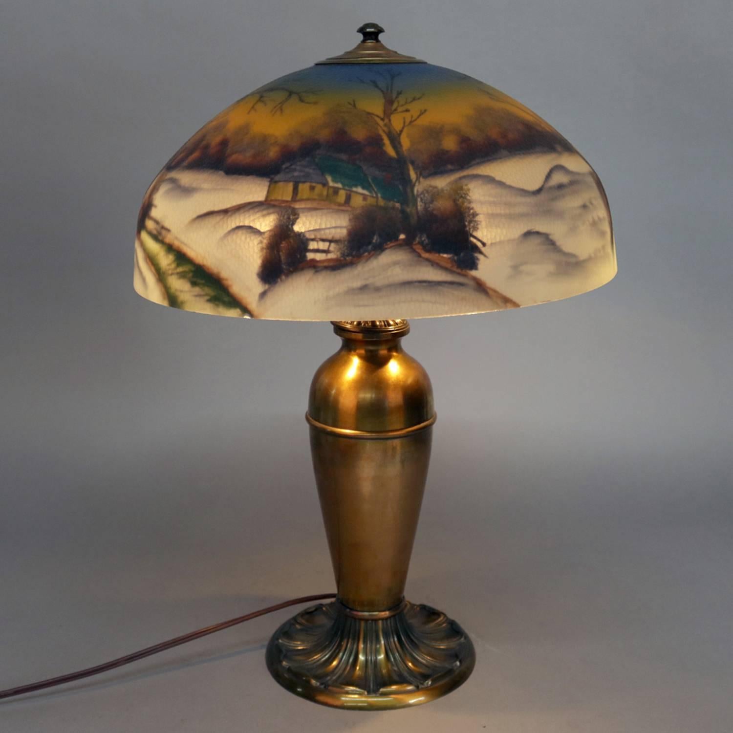 Antique Handel School table lamp features Pittsburgh style reverse painted glass dome shade with winter landscape scene with snow and cabin, cast amphora form brass base, dual pull chain lights, circa 1920

Measures: 24