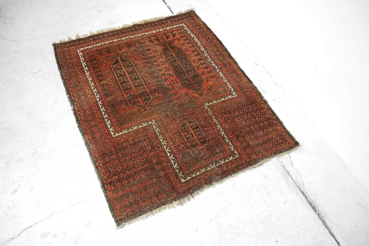 Ce tapis baloutche antique fait à la main a été fabriqué au début du 20e siècle. Le tapis est de couleur rouge foncé traditionnelle avec des motifs géométriques et tribaux. Ce tapis noué à la main est unique, d'une beauté et d'une harmonie de