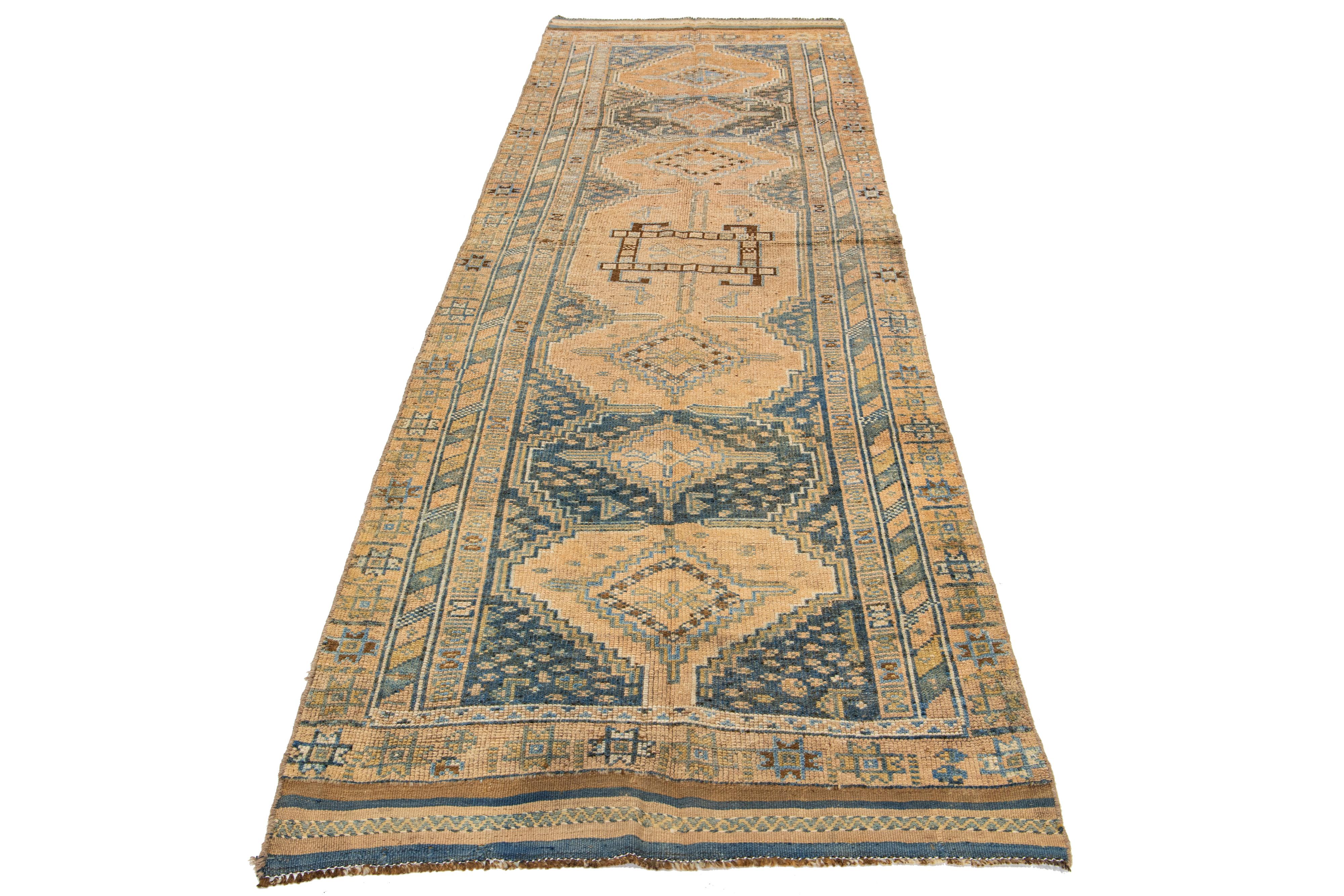 This beautiful 20th-century Heriz hand-knotted wool runner has a tan-colored field. The piece features stunning blue and brown accents in a gorgeous tribal design.

This rug measures 3'6