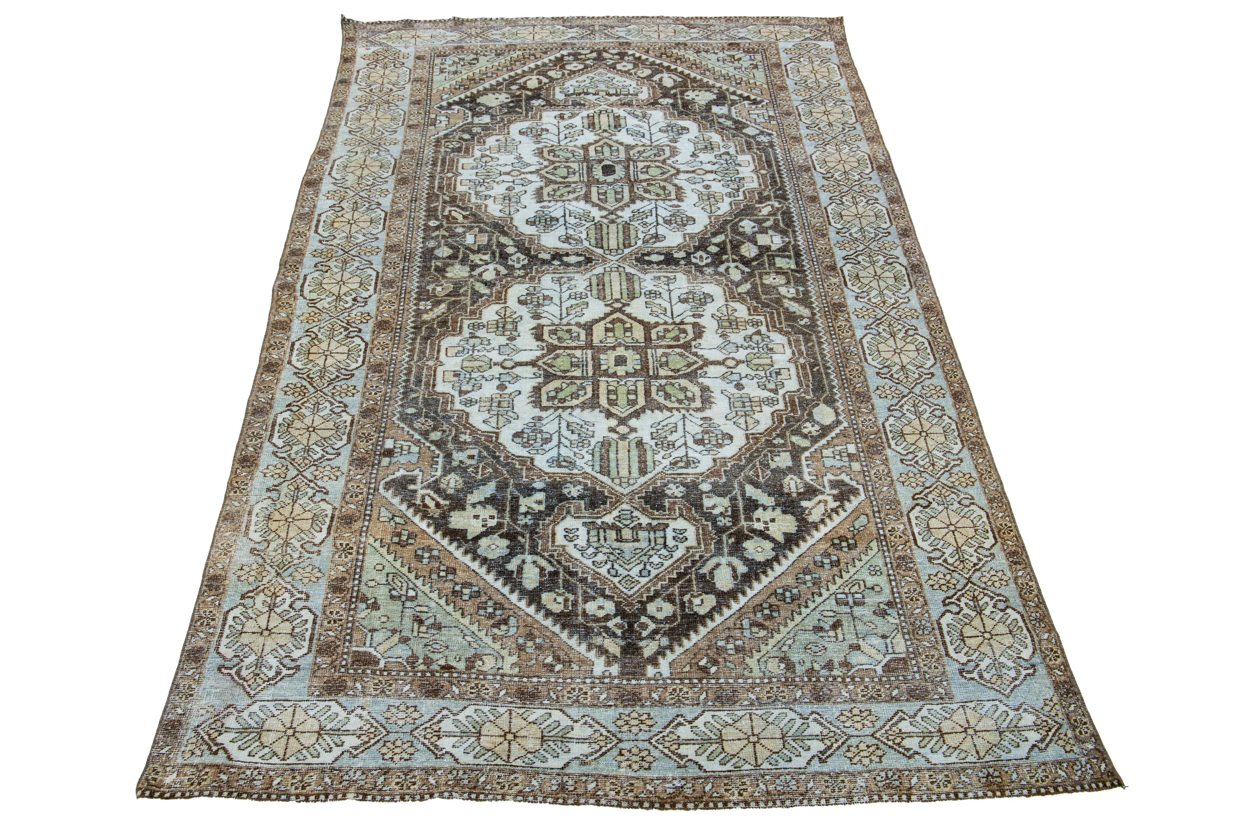 Beautiful antique Persian Mahal hand-knotted wool rug with a brown color field. This piece has a blue-designed frame with ivory, green, and blue accents in a gorgeous medallion floral design.

This rug measures 5'6
