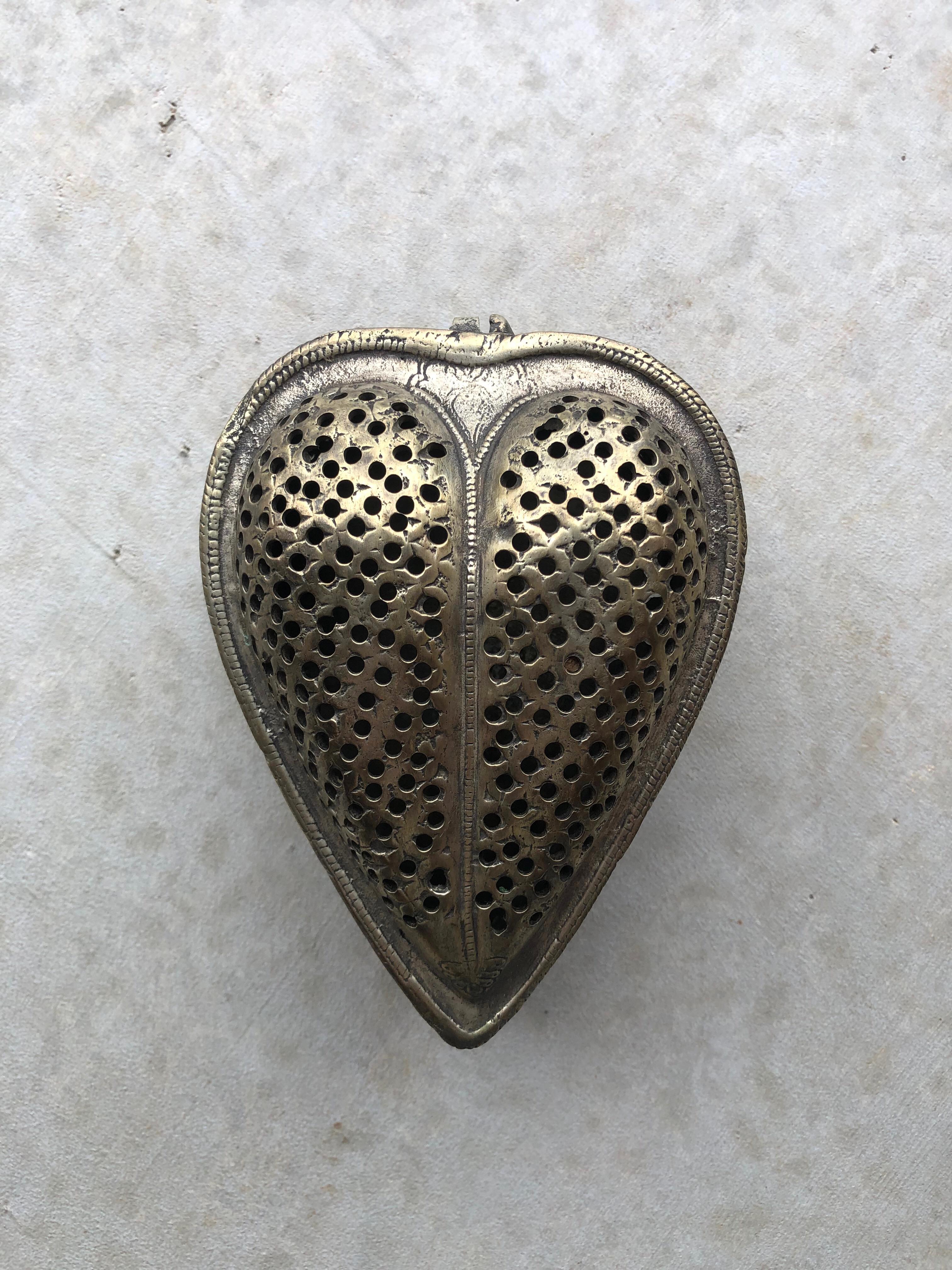 Sweet and sentimental heart shaped metal box. With a subtle patina, this antique piece features a domed heart lid, with a hinge, and punched metal details. Perfect as a keepsake memory box or as a sweet catchall piece.

4