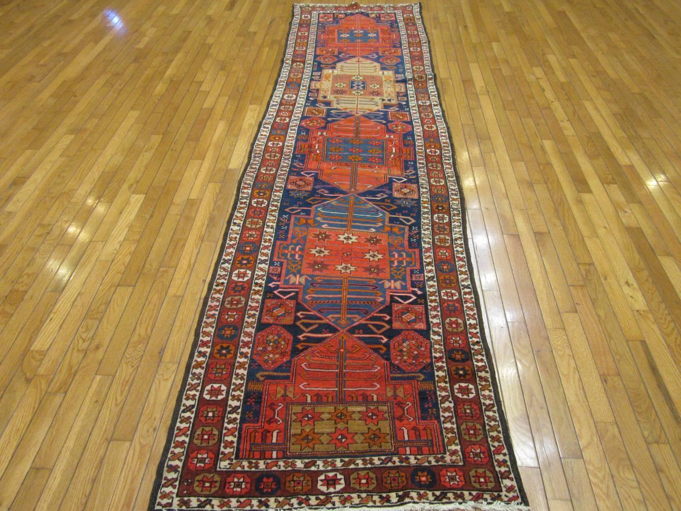 This is an antique hand-knotted runner rug from northwest Iran (Persia) with a simple multi medallion nomadic design in rich natural dye colors. It is made with wool pile and cotton foundation. The rug measures 3' x 10' 10'' and in great condition.