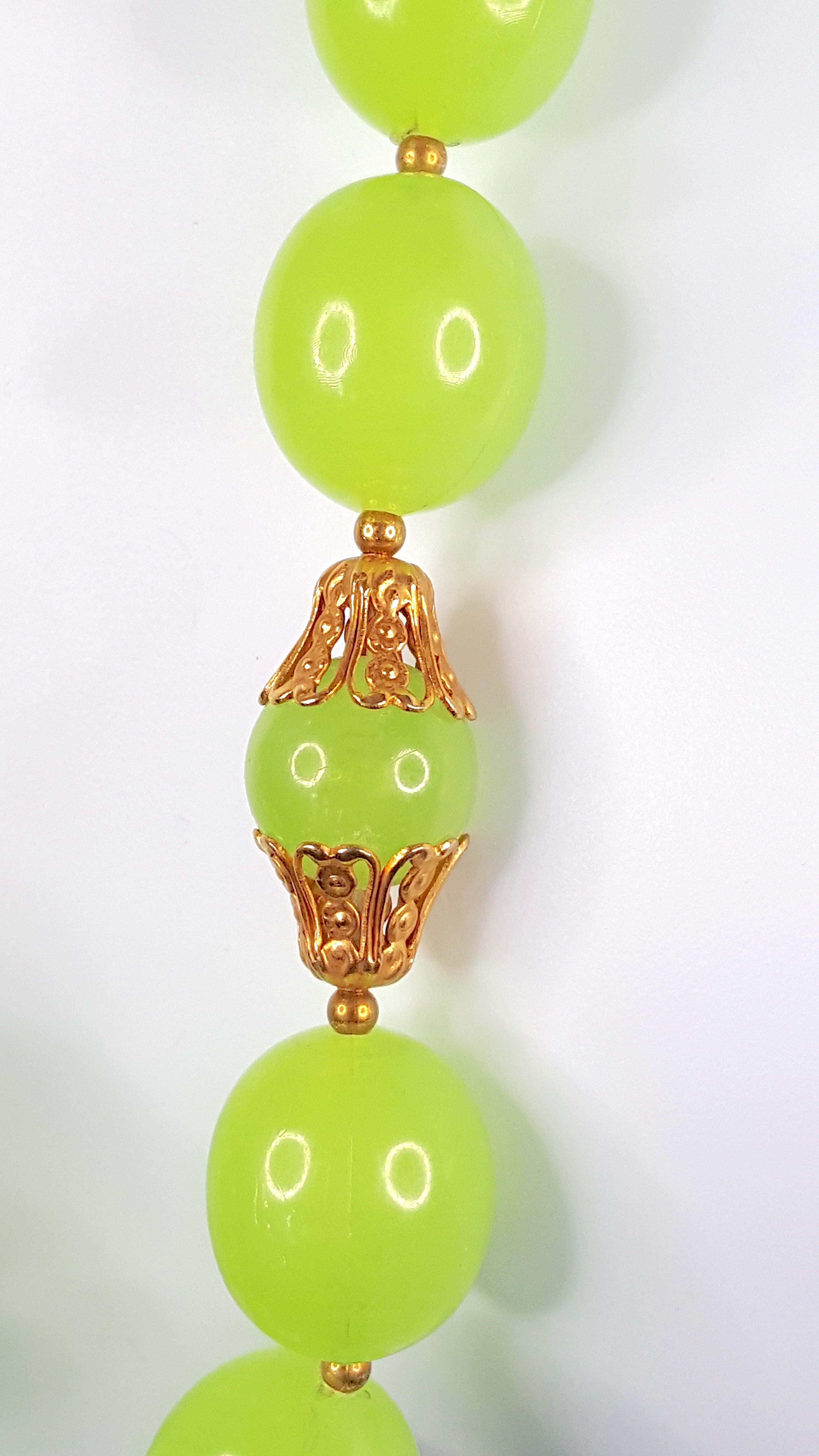 Ce collier antique en verre pressé à la main présente de grosses perles semi-translucides de couleur vert raisin, couronnées d'un filigrane en laiton doré. D'après la combinaison des coutures de perles, du fermoir à anneau à ressort et des pièces