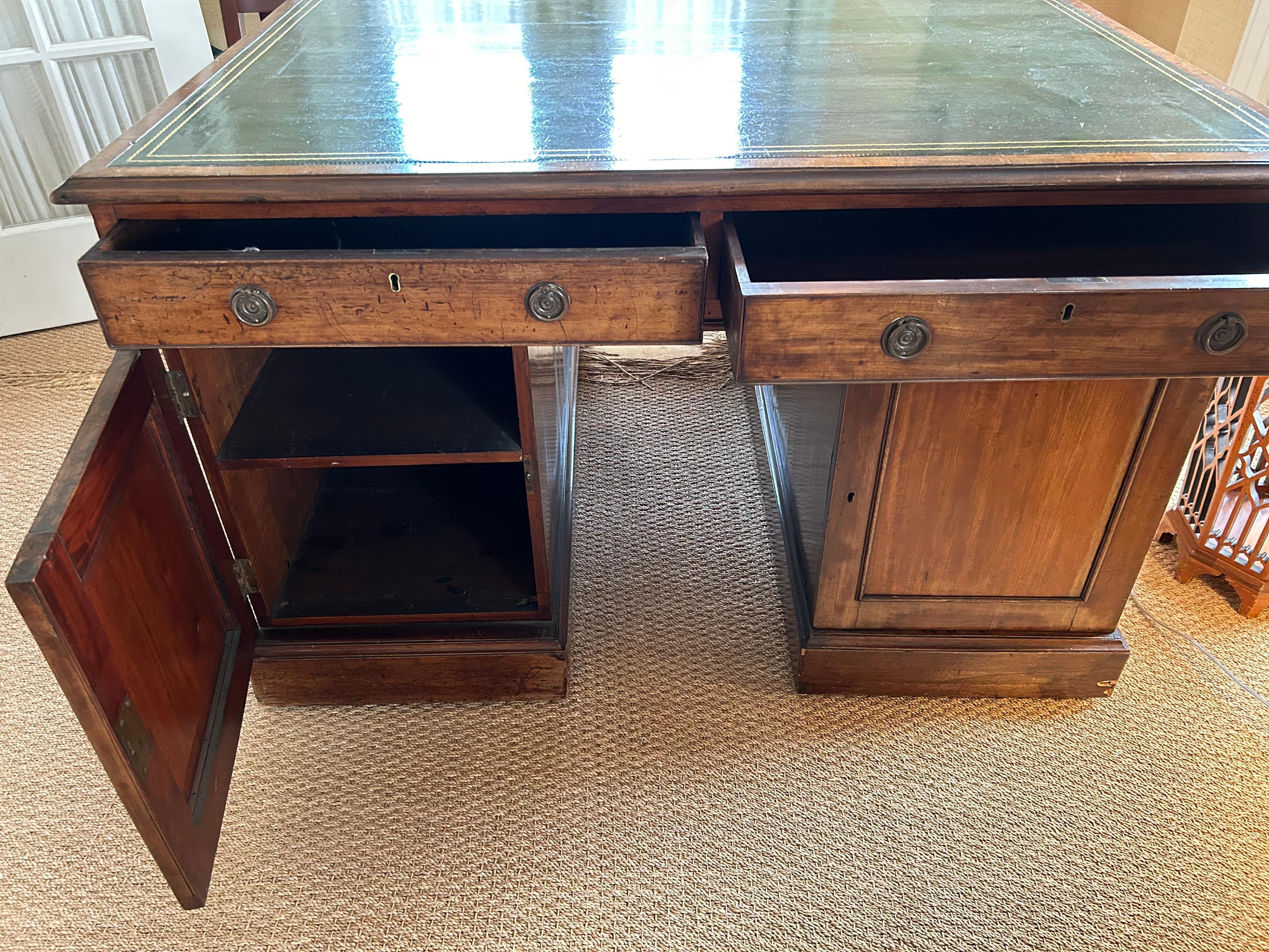 Precioso escritorio inglés antiguo de caoba, de gran carácter, con una lujosa tapa de cuero verde kelly repujado.  Un lado tiene 7 cajones, el otro 2 cajones sobre puertas paneladas con almacenaje interior.  La abertura mide 14,5 x 23 hasta el