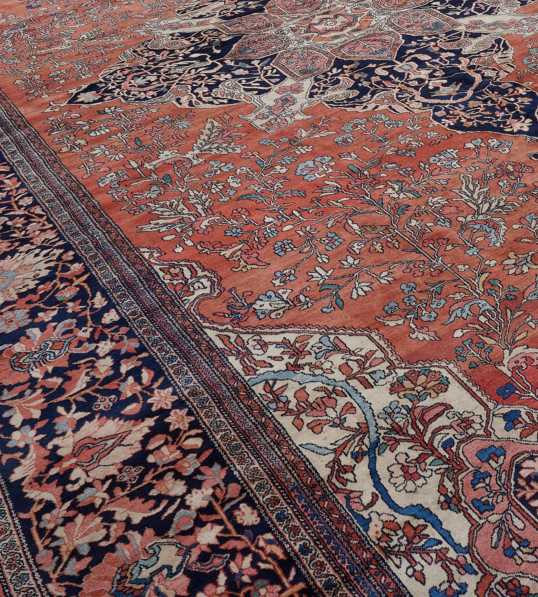 This Fereghan rug has a brick-red field with a vase motif at each end issuing a floral spray and surrounded by a delicate polychrome floral vine around a central indigo-blue cusped medallion with shield palmettes containing a central brick-red