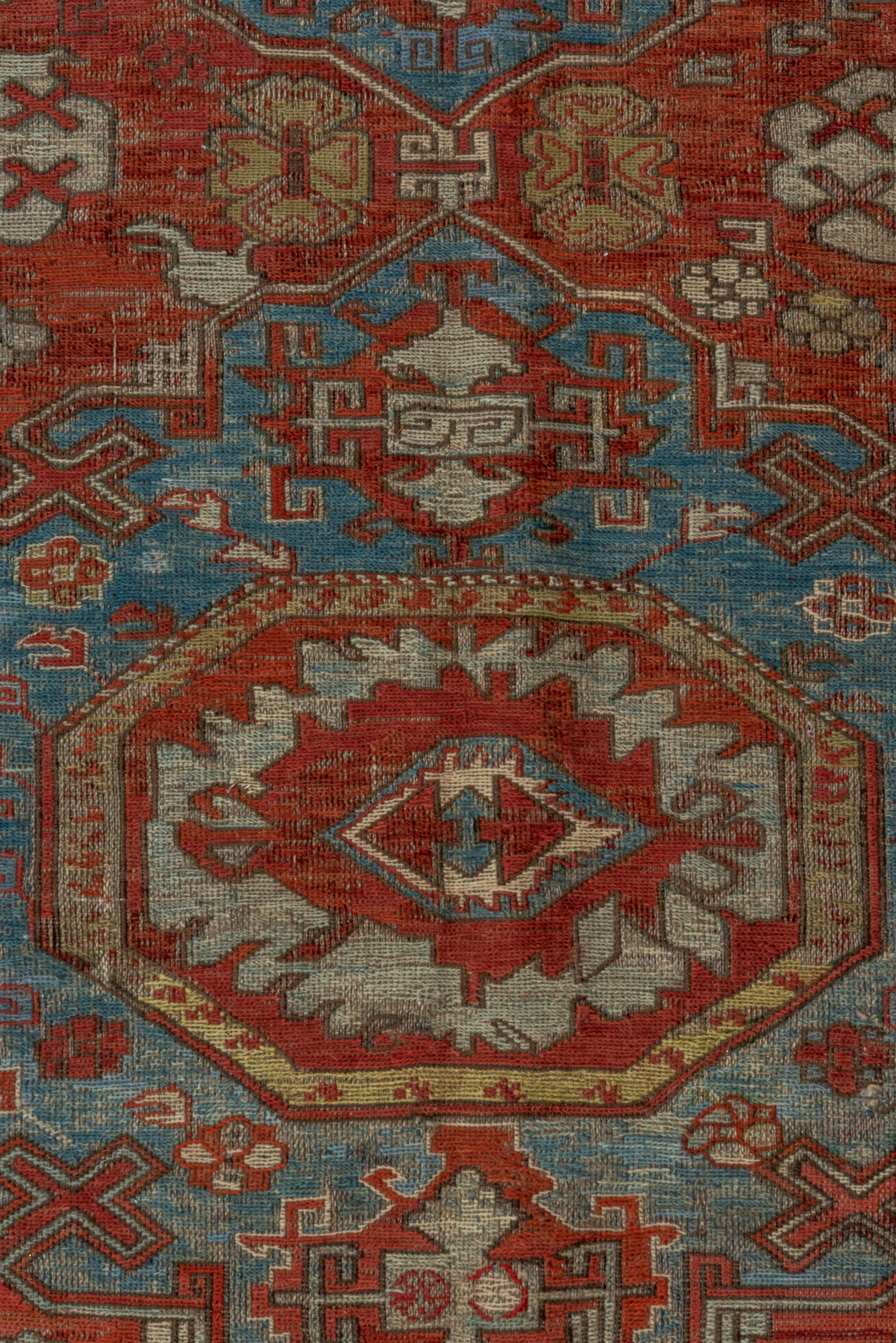 Ce tapis Sumak ancien, réalisé de main de maître, présente un remarquable treillis de médaillons de boucliers et de palmettes angulaires sur un riche champ rouge rouille. De doux accents céladon, bleu pâle et ivoire sont élégamment tissés dans les