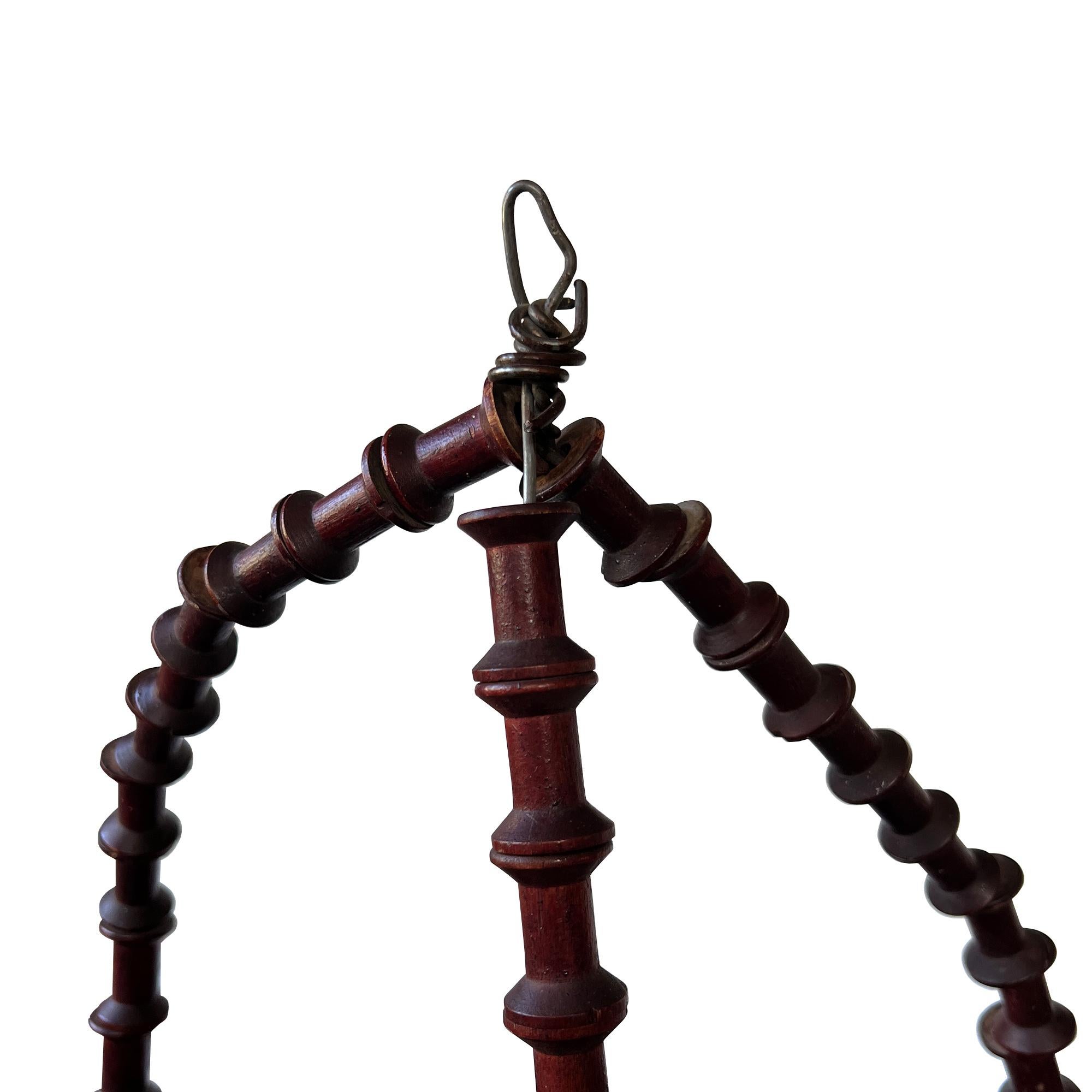 A beautiful antique hanging corner shelf or étagère, featuring finely spool-turned supports and five graduated triangular shelves in their original oxblood red painted finish. The craftsmanship and patina suggest a late 19th to early 20th-century