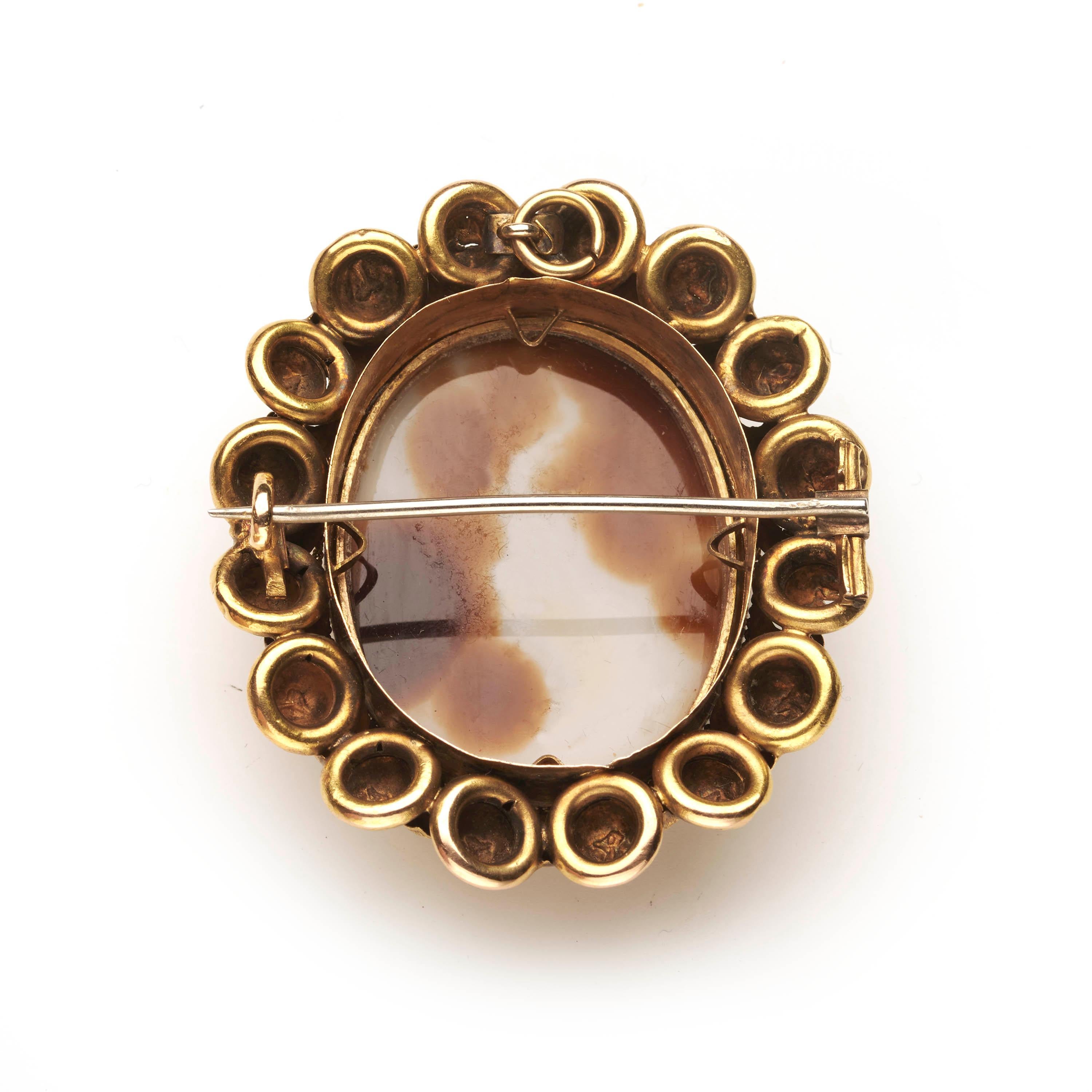 An antique cameo brooch, with a hardstone sardonyx cameo of a lady, with a Roman hairstyle, on a brown background, in a double row gold frame, with a rub over setting, a twisted chain and engraved, stamped foliate surround. There is a loop at the