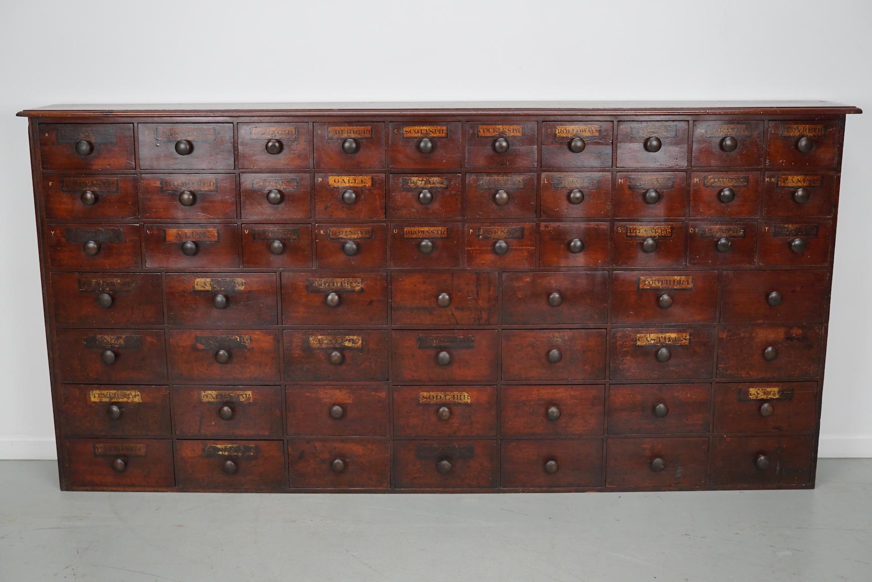 This apothecary bank of drawers was designed and made in England, late 19th century. It is made from solid wood with hand-painted labels and wooden knobs. The cabinet has retained a rich patina with some natural distressing. The drawers are fully