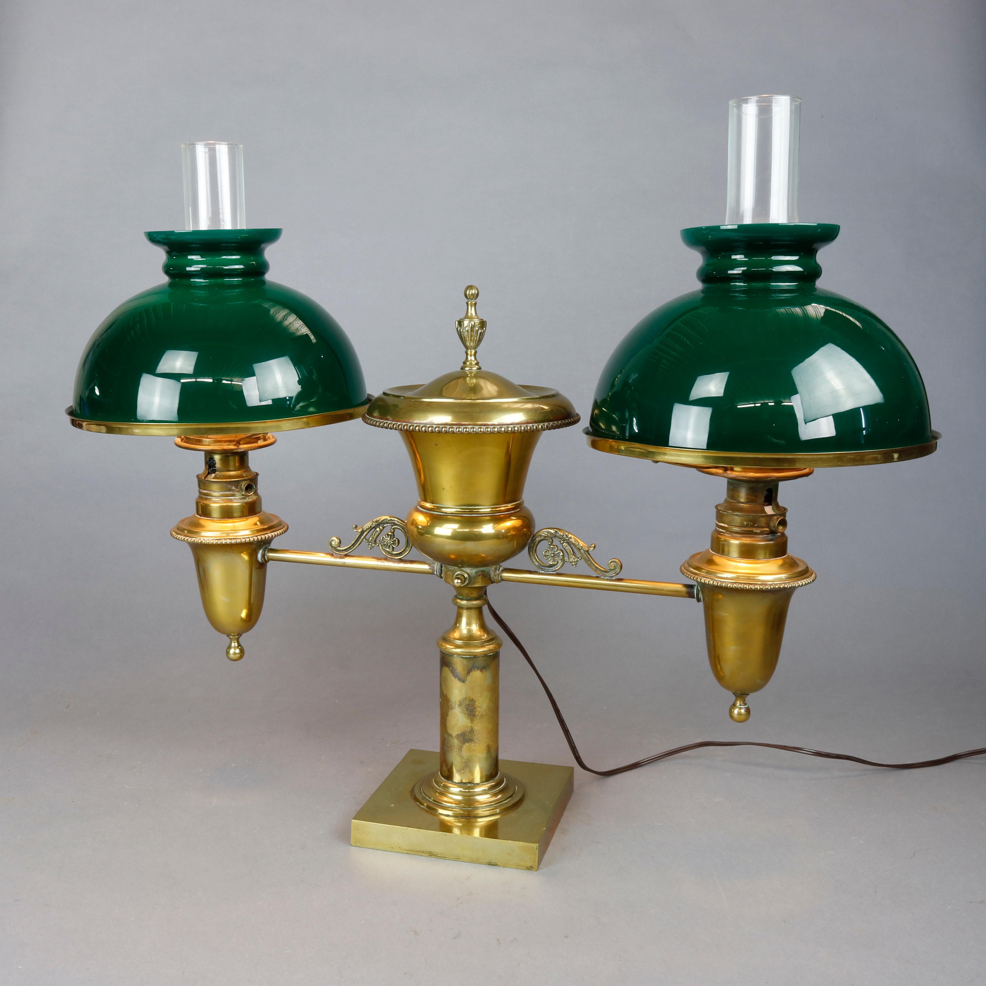 An antique Harvard School student lamp offers brass frame with central Classical urn font having flanking scroll elements and double lights with emerald cased glass shades, electrified and working, circa 1890.

Measures: 23