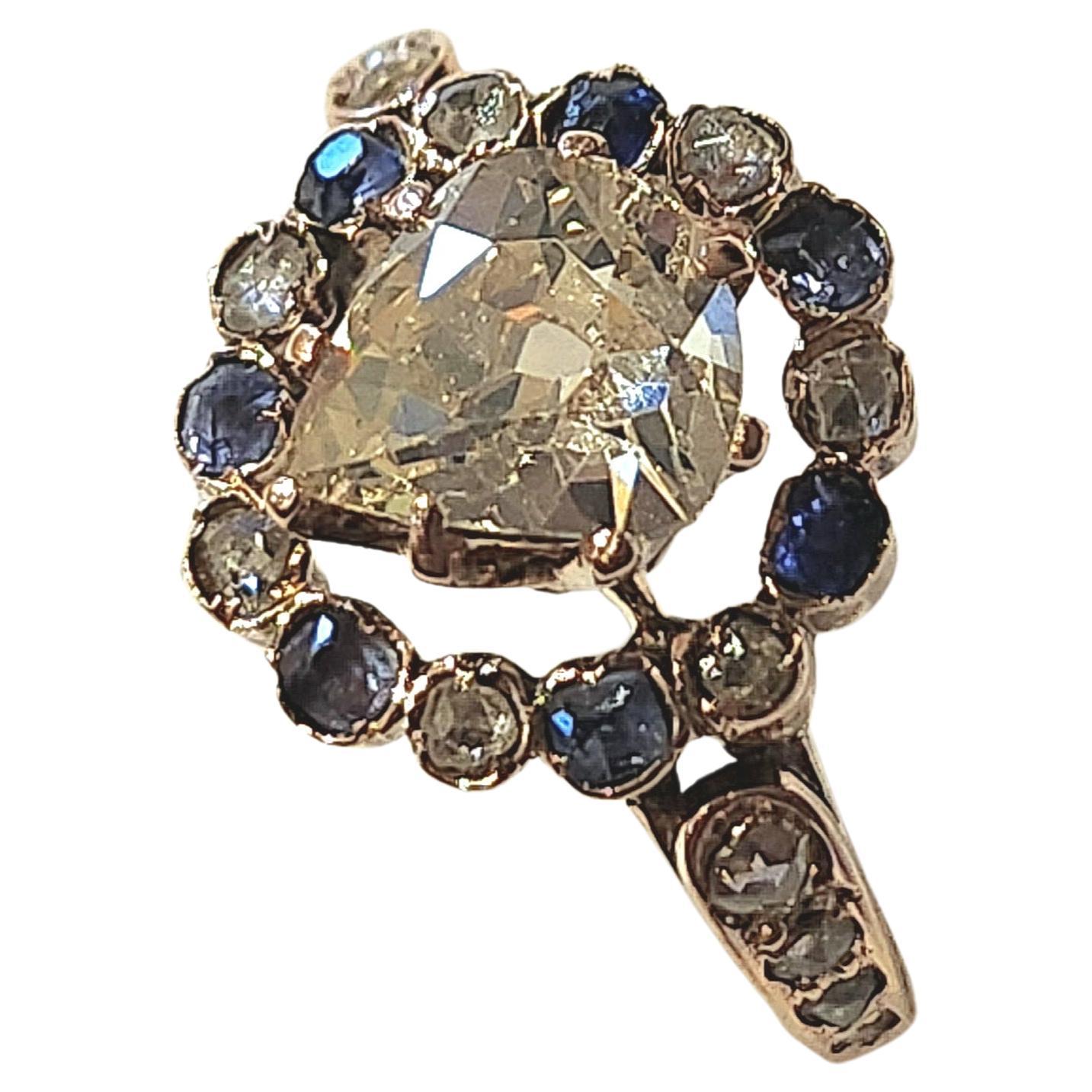Antique ring centered with heart shape old cut diamond diameter 7.5mm×7mm estimate diamond weight 1.30 carat white color vs clearity excellent spark flanked with smaller diamonds and natural blue sapphire in 14k gold setting ring was made in europe