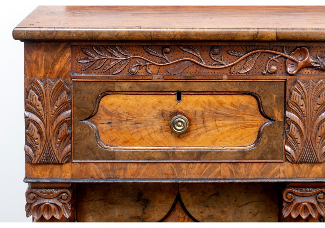 Antique buffet two tone cabinet with paneled sides, arched doors below one long and two short drawers, carved with trailing vines with florals, palmettes above spiral twist columns and resting on stylized paw feet. The doors open to reveal shelf
