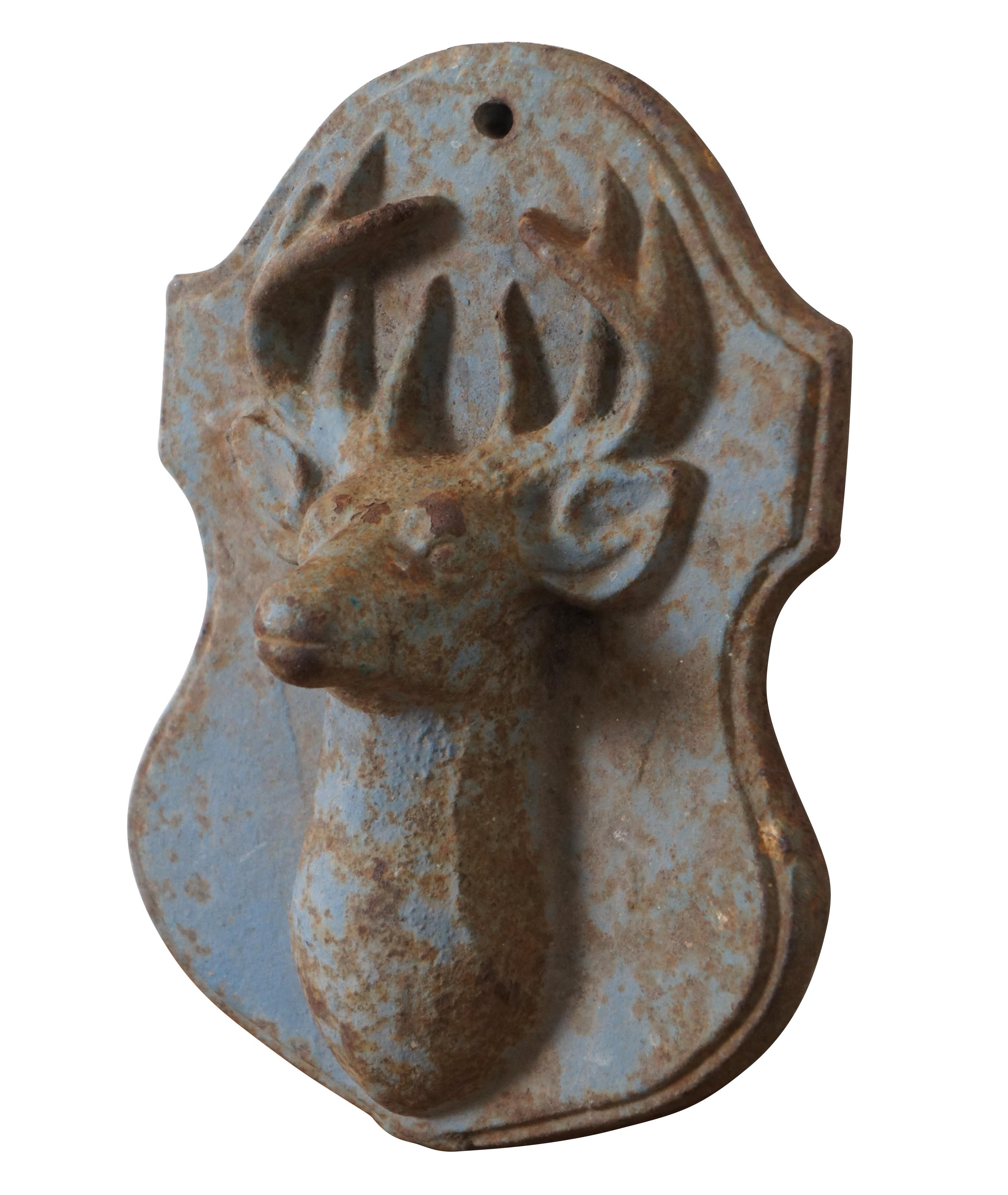 Heavy vintage cast iron wall hanging plaque in the shape of a shield with a rounded top, mounted with the head of a buck / deer. Painted light blue.