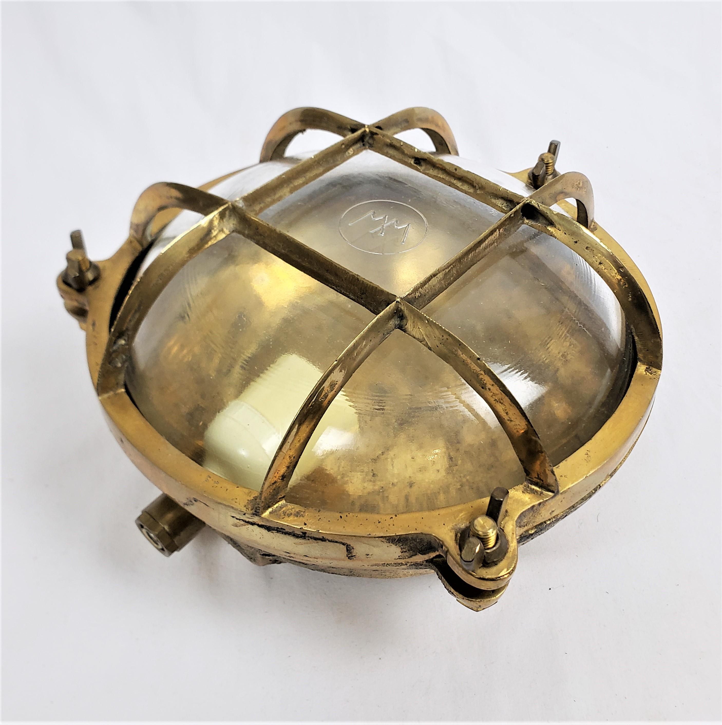This antique brass nautical styled light is unsigned, except for some markings on the lens, but presumed to have originated from Germany and date to approximately 1920 and done in the period Art Deco style. The housing and cage are composed of heavy