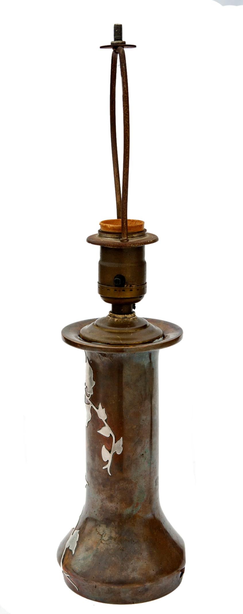 Vase du début du 20e siècle en bronze avec des vignes et des feuilles recouvertes d'argent sterling par le célèbre studio Arts & Crafts Heintz Metalworks.
Câblage refait à neuf pour une ampoule standard.