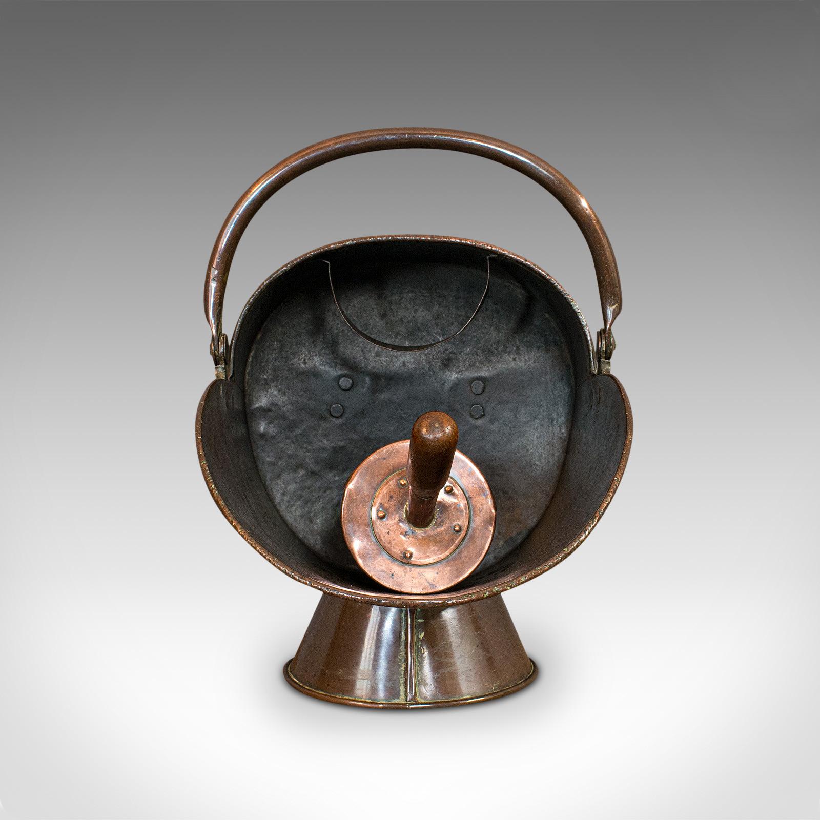 This is an antique helmet coal scuttle. An English, copper fireside bucket, dating to the Victorian period, circa 1870.

Attractive antique scuttle and companion scoop
Displays a desirable aged patina
Rich copper tones and hues, superb