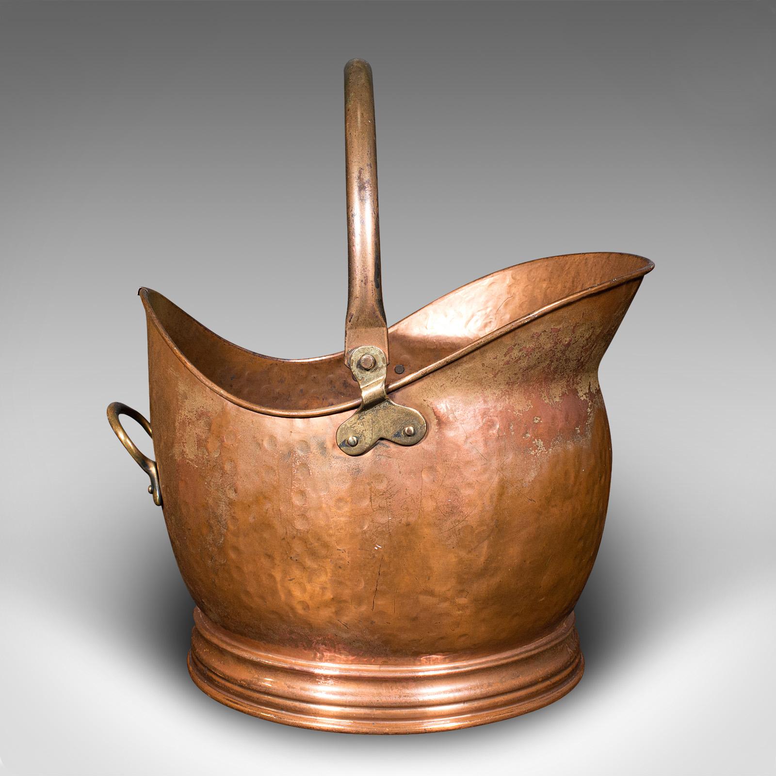 This is an antique helmet coal scuttle. An English, copper fireside store or fuel keeper, dating to the late Victorian period, circa 1900.

Delightfully traditional scuttle with great hand-beaten finish
Displays a desirable aged patina and in