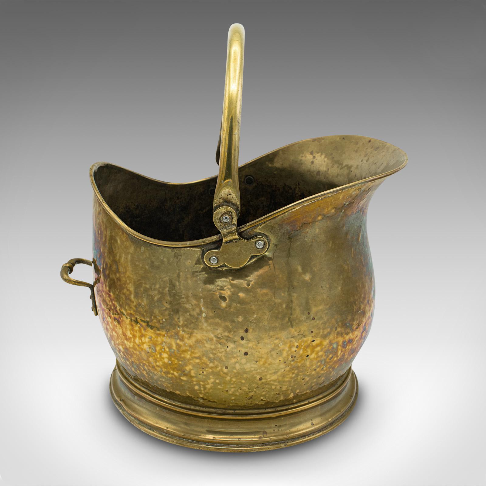 This is an antique helmet scuttle. An English, brass coal bucket or fireside bin, dating to the late Victorian period, circa 1880.

Attractive helmet shaped scuttle with appealing beaten finish and colour
Displaying a desirable aged patina and in