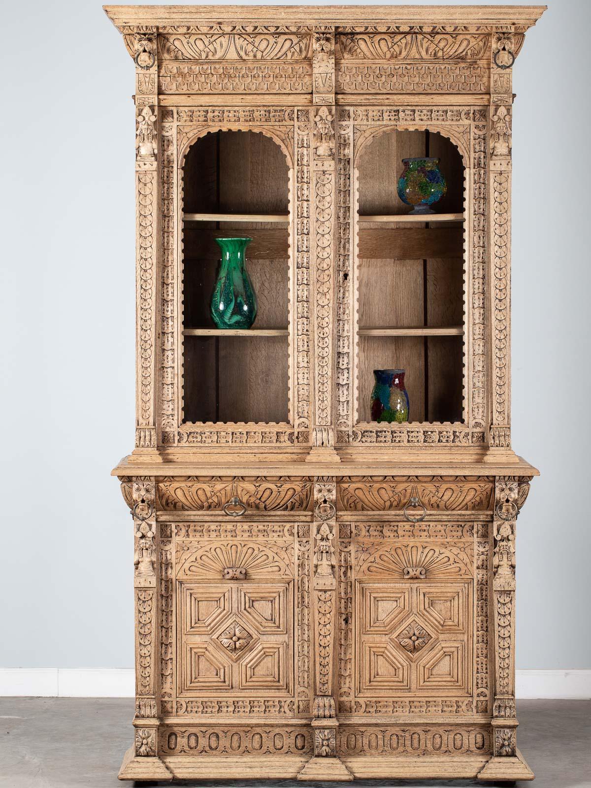 A handsome antique French Henri II style oak bibliotheque bookcase display cabinet circa 1880. Please take a moment to examine the lavish carving seen across the facade and sides of this bookcase and enlarge the photographs to see the details in