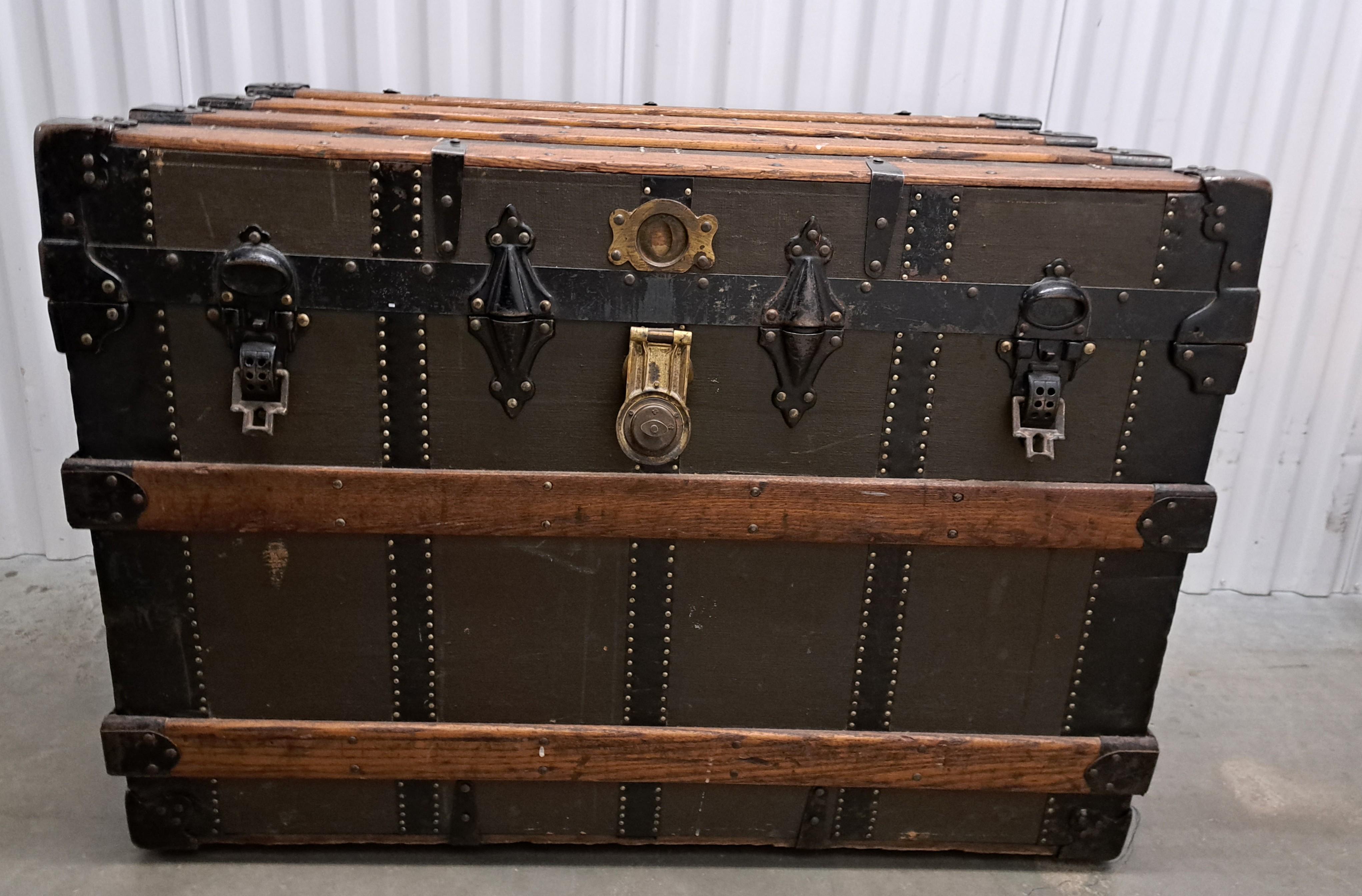 This is a classic American style steamer trunk with wooden slats and brass fittings. Trunk has two custom compartment trays that are in good condition. With brass label stating Henry Likly and Co. Rochester New York.
