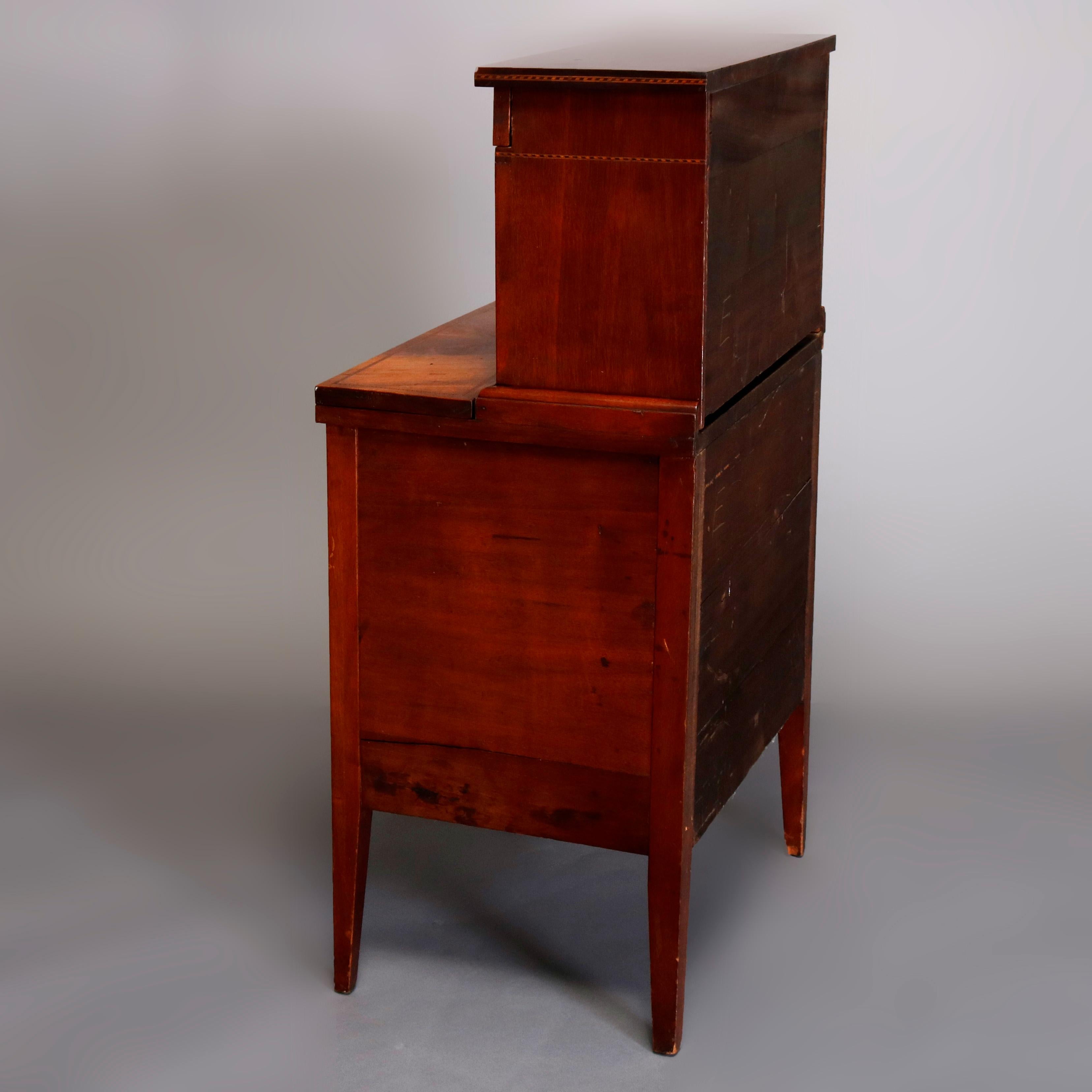 An antique English Hepplewhite style Bureau à Gradin Tambour secretary desk offers flame mahogany construction in diminutive form with tower having tambour doors opening to reveal interior storage drawers and pigeon holes and surmounting drop front