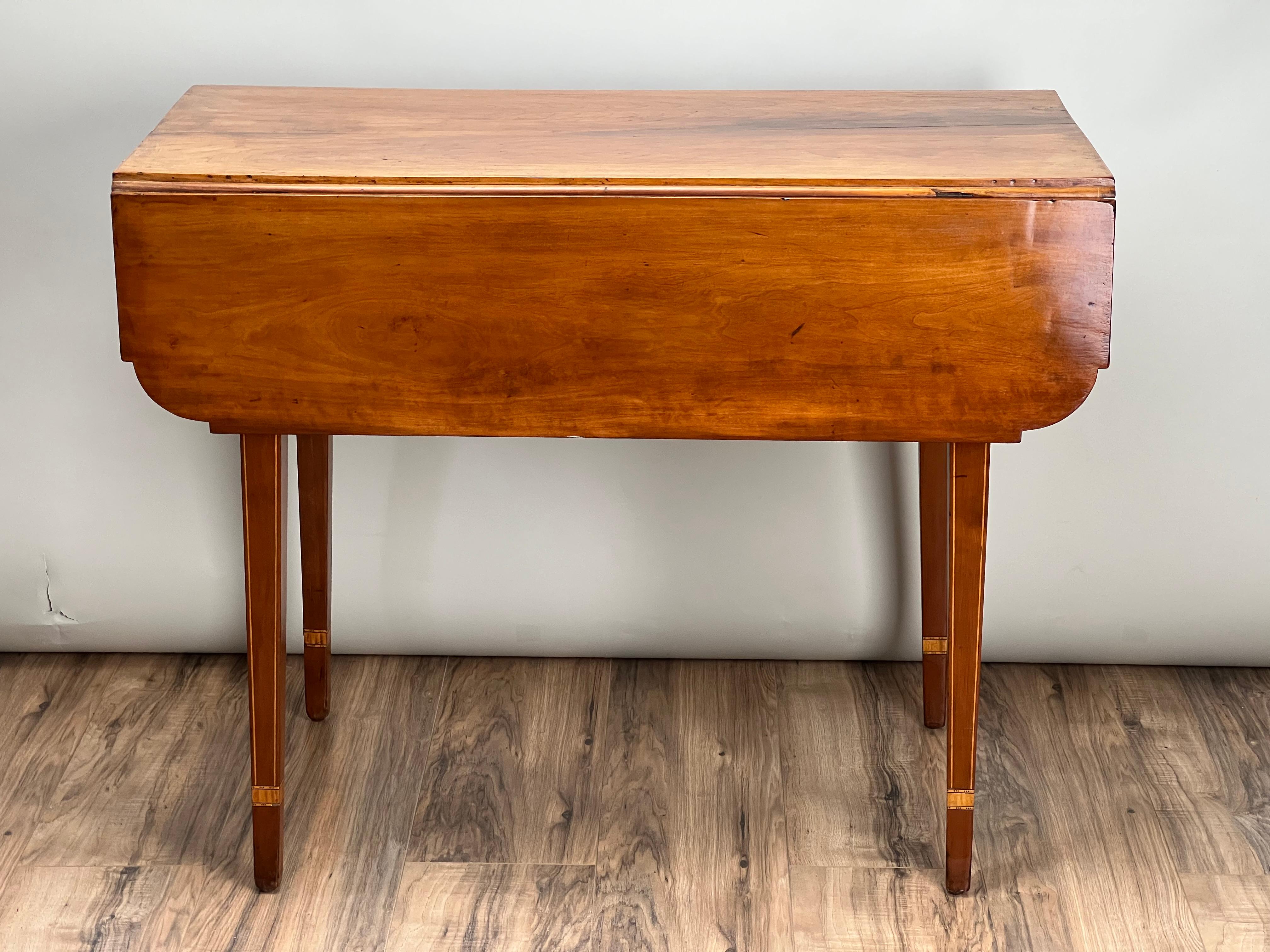 Cette ancienne table à feuilles tombantes en érable marqueté de Hepplewhite, datant du début du XIXe siècle, est un exemple raffiné de design néoclassique. Fabriquée en érable, la table présente des détails incrustés en bois satiné et en ébène,