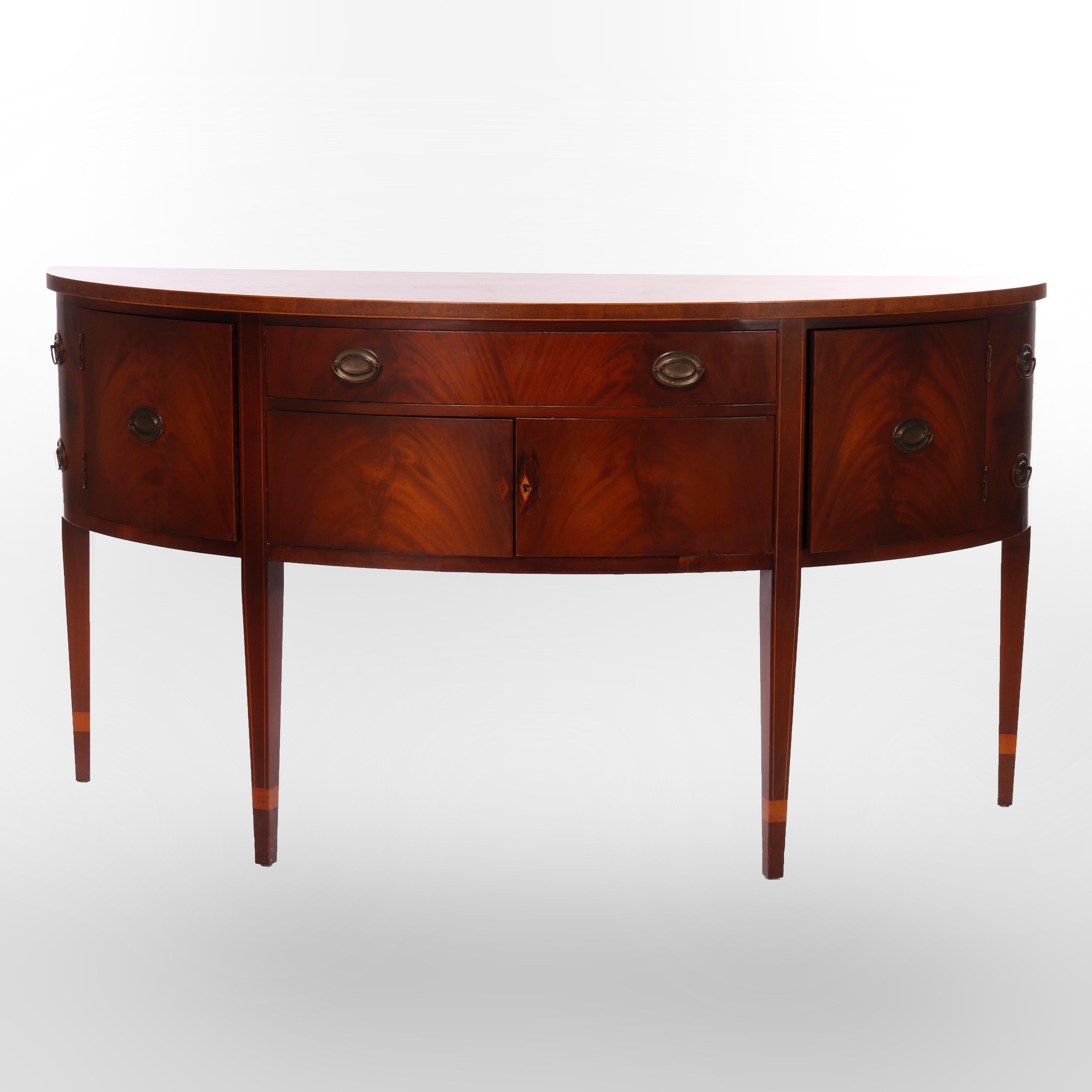 An antique sideboard by Kittinger offers flame mahogany construction in demilune form with case having drawers and cabinets, satinwood inlay banding and raised on square and tapered legs, maker label as photographed, c1930

Measures - 38.25'' H x