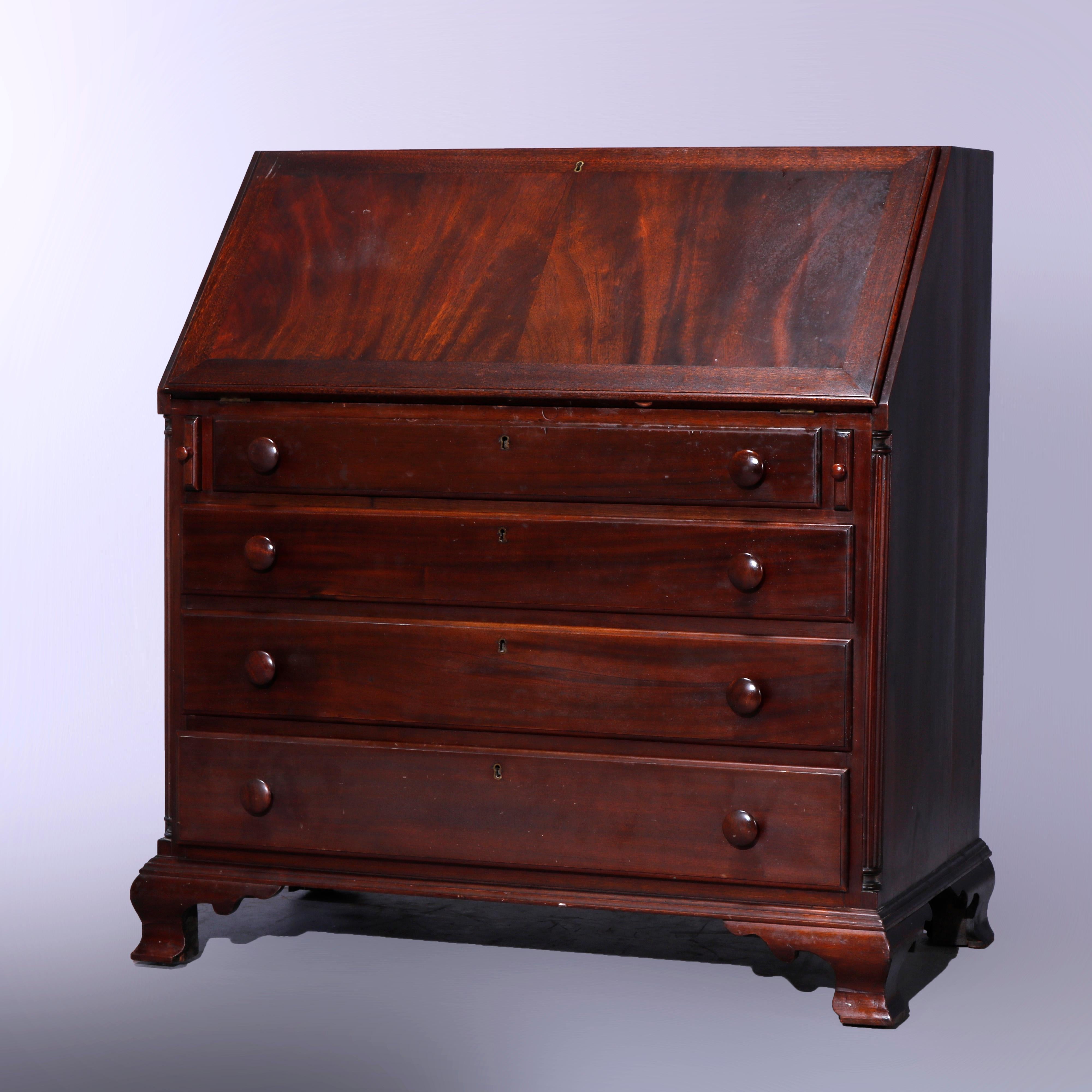 An antique Hepplewhite style desk offers flame mahogany construction with bookmatched drop front opening to writing surface and interior pigeon holes and storage compartments, over case with graduated long drawers and raised on ogee bracket feet,