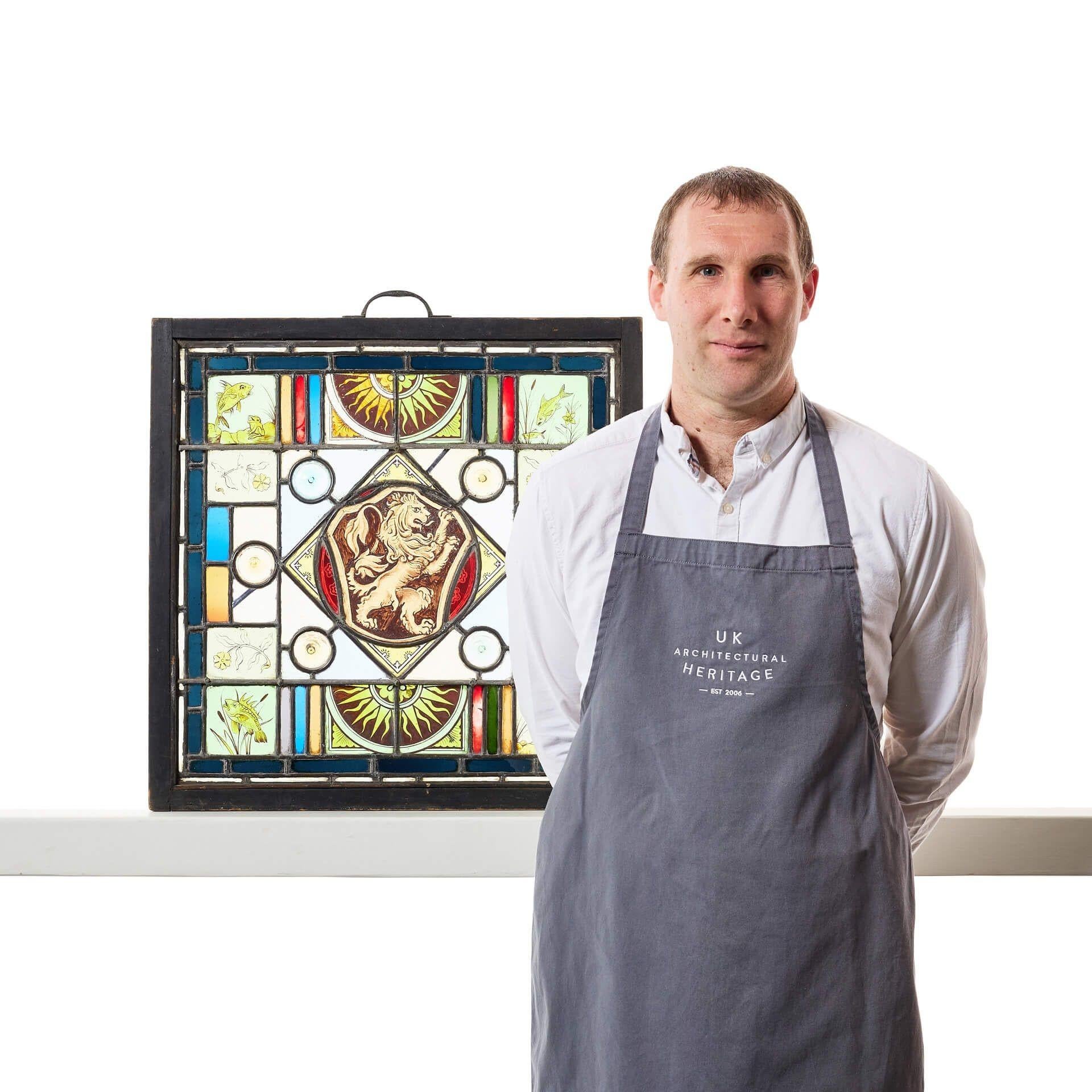 A antique framed stained glass panel depicting a heraldic rampant lion to the centre, the perfect vibrant feature for any period property.

Housed in a painted softwood frame, the hand painted sun rays, fish and floral multi panels to the border