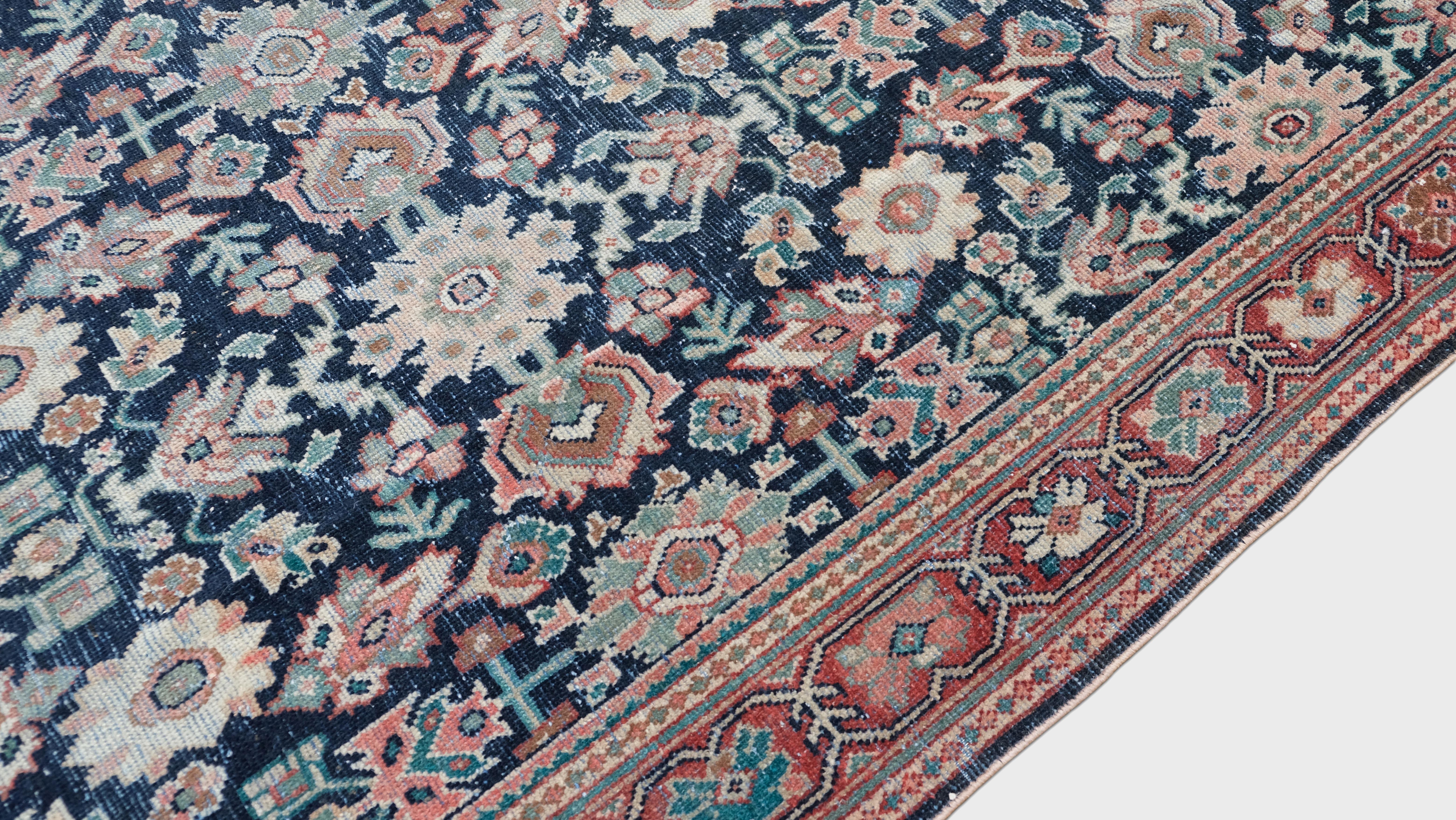 Dieser antike, handgeknüpfte Wollteppich ist ein atemberaubendes Beispiel traditioneller Handwerkskunst. Er zeigt ein kompliziertes Herati-Blumenmuster vor einem tiefen Farbfeld. Das sorgfältig gewebte, symmetrische Muster besteht aus miteinander