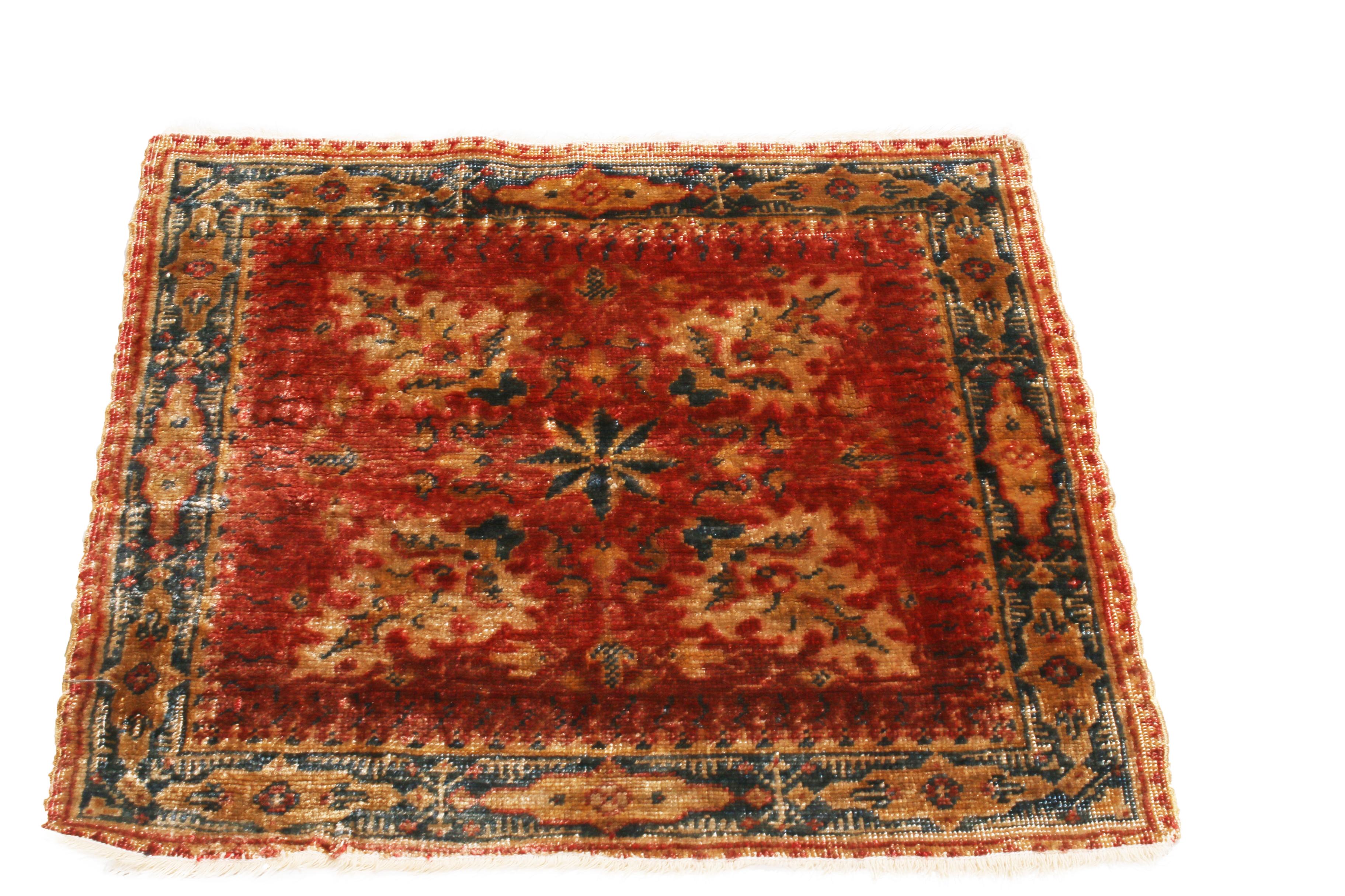 Hand knotted with a luminous, high-quality silk in a combination of vivid and rustic red and beige colourways, this antique Hereke rug originates from Turkey in 1880, crafter in a perfectly square body complemented by its subtly rich royal blue
