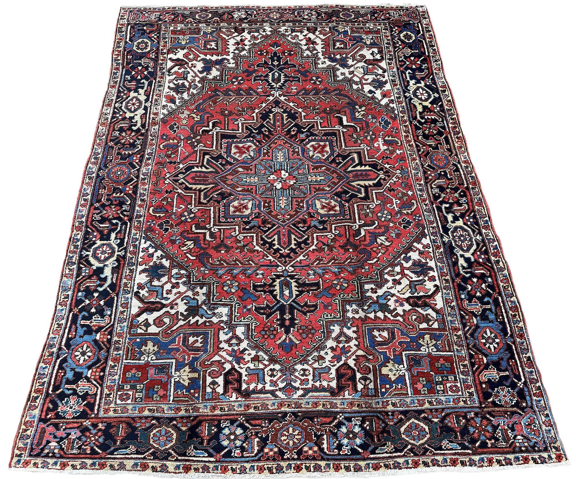 Un joli tapis Heriz ancien, tissé vers 1920, dans un petit format difficile à trouver. Le motif présente un grand médaillon géométrique sur un riche champ de terre cuite entouré d'une bordure classique d'indigo profond. Des couleurs secondaires très