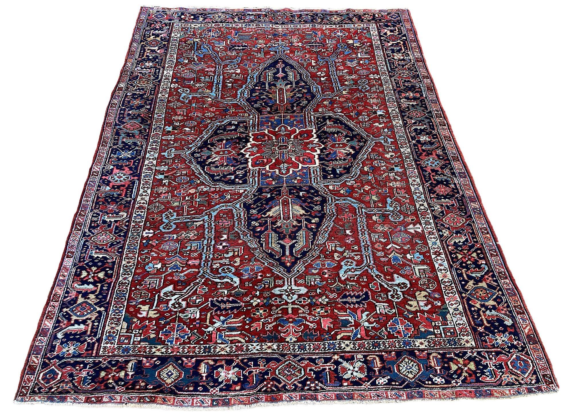 A wonderful antique Heriz carpet, hand woven circa 1920. The design features an unusual geometrical central medallion surrounded by stylised flowers and vines on a rich terracotta field and indigo border. A very decorative carpet with great