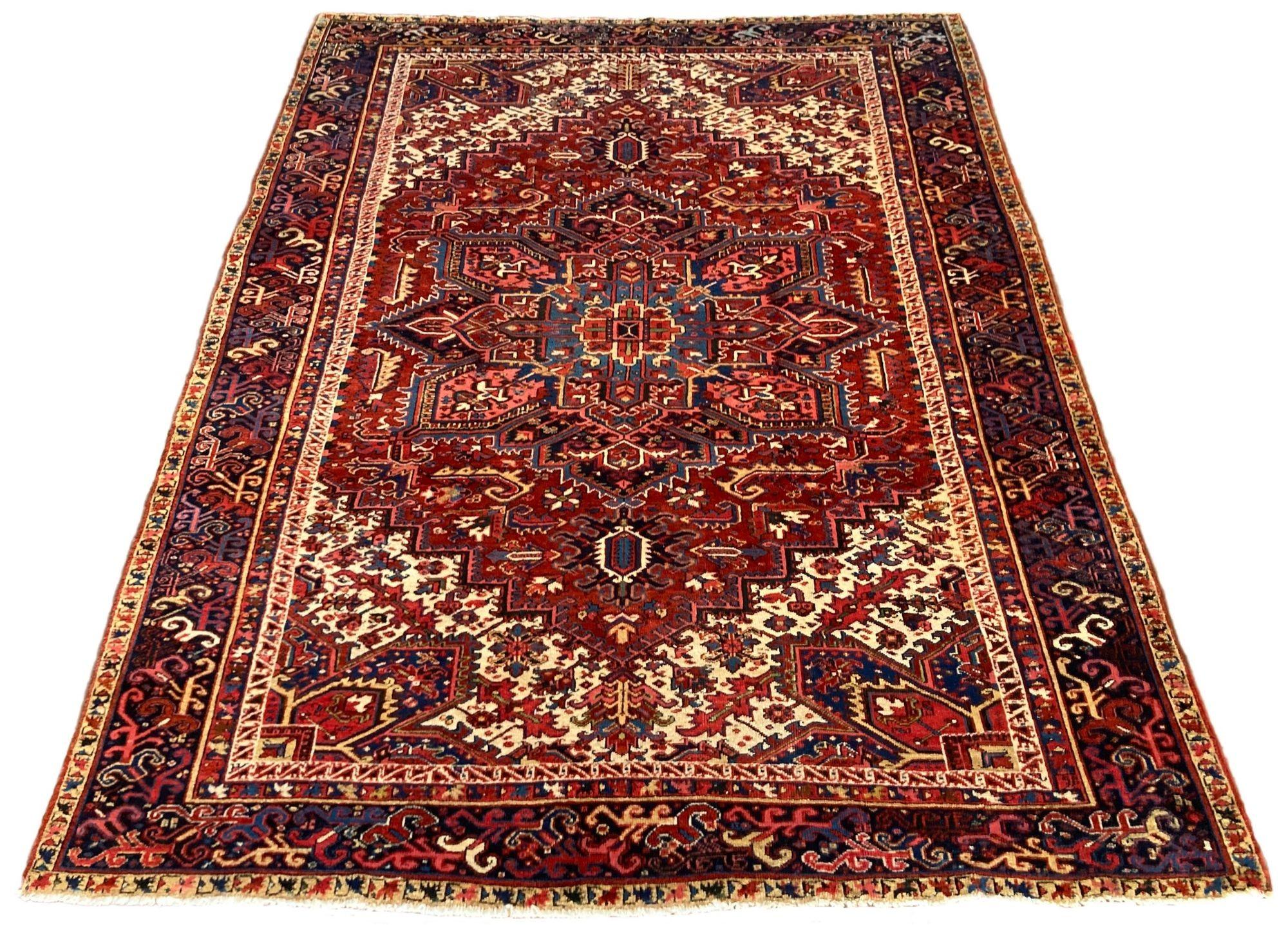 Ein fabelhafter antiker Heriz-Teppich, handgeknüpft um 1910 mit einem traditionellen geometrischen Muster auf einem Terrakotta-Feld und einer tiefen indigoblauen Bordüre. Einige interessante Designelemente, darunter ein hübsches Bordürenmuster und