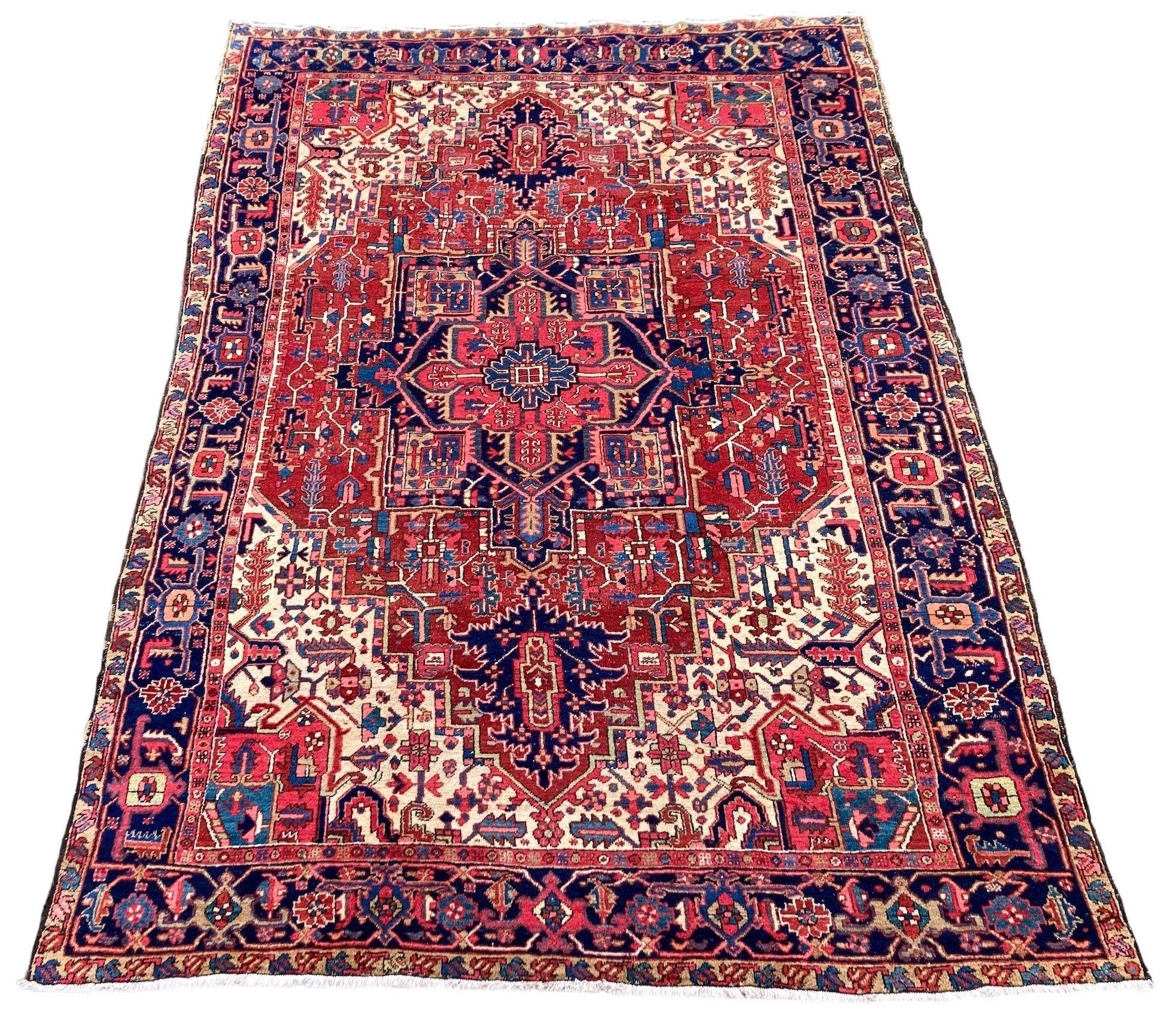 A beautiful antique Heriz carpet, handwoven circa 1920 with a large geometrical medallion on a terracotta field and deep indigo border. Fabulous secondary colours, especially the large ivory corners and a highly decorative piece.

Size: 3.36m x