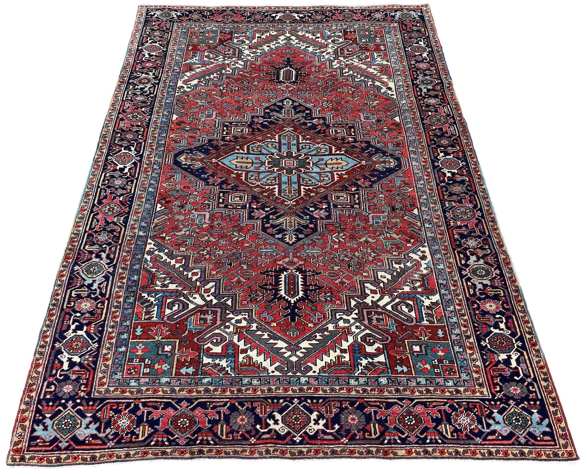 A fabulous antique Heriz carpet, woven circa 1920. The design features a large geometrical medallion on a soft terracotta field surrounded by a classic deep blue border. Very attractive secondary colours, particularly the sky blue in the medallion