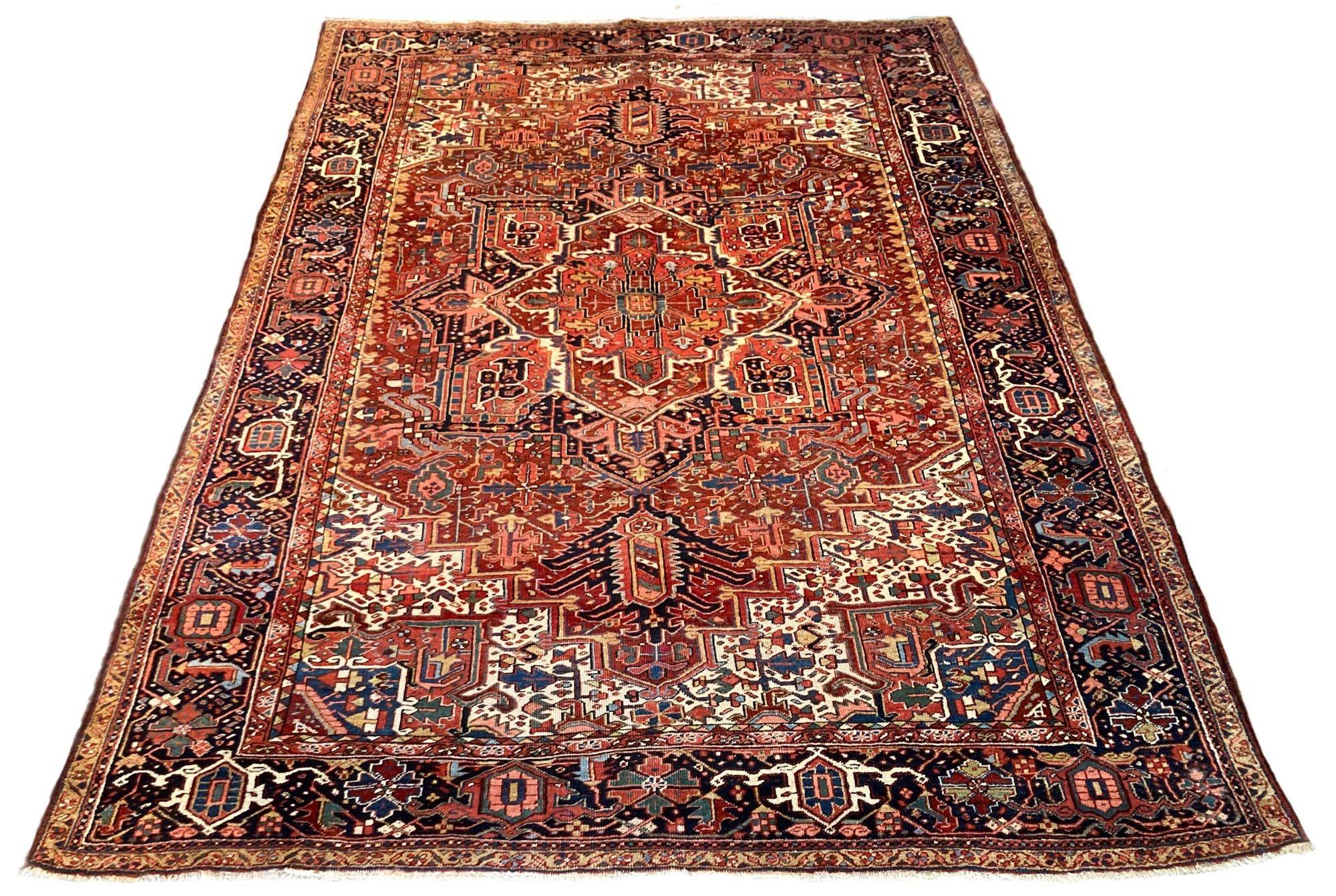 Un meraviglioso tappeto Heriz antico, tessuto a mano intorno al 1920. Il design presenta un grande medaglione centrale geometrico circondato da fiori e viti stilizzate su un ricco campo di terracotta. Alcuni interessanti elementi di design sono il