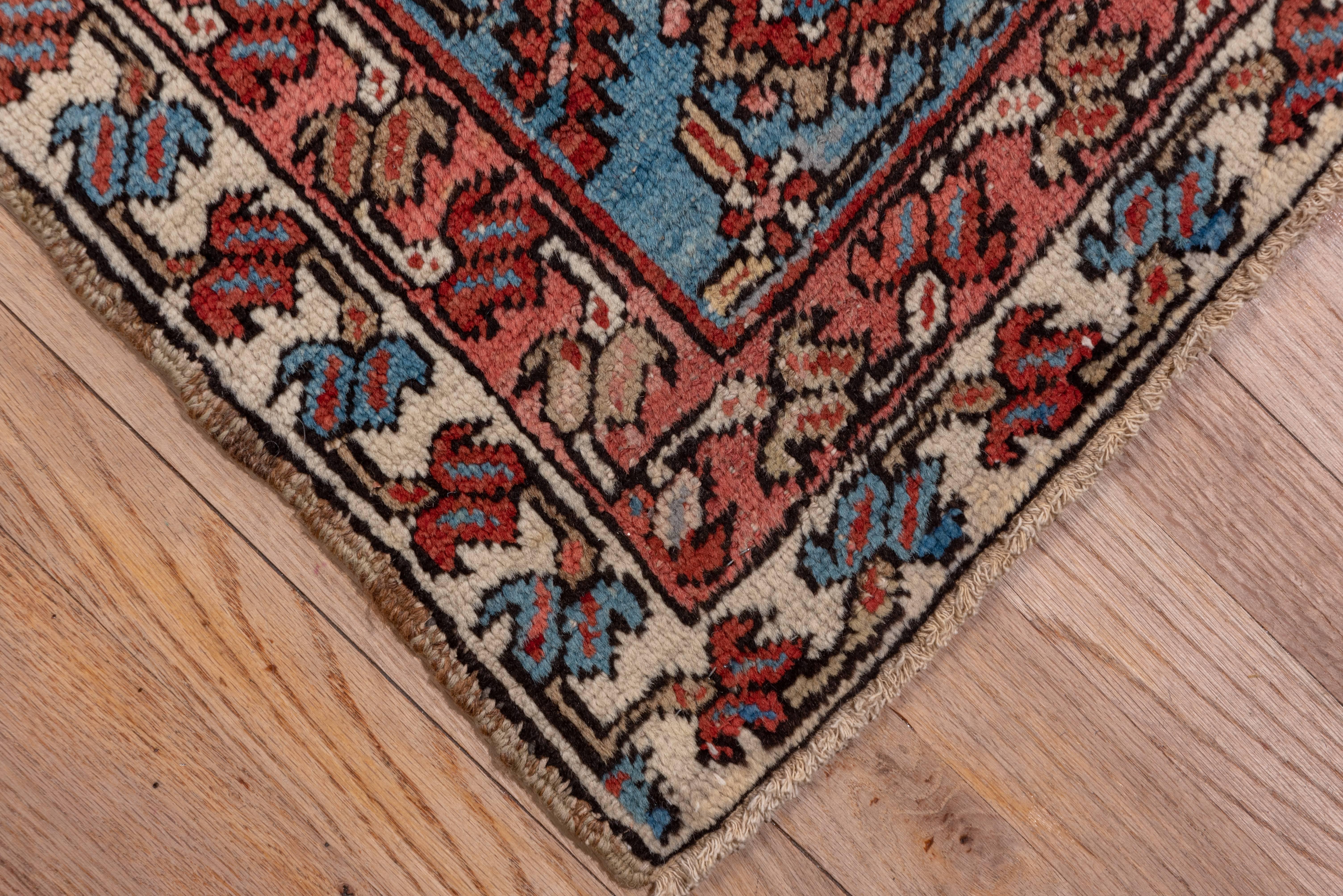 Of higher Serapi grade, this NW Persian village carpet displays a terracotta red subfield centred by a palmette pendanted navy nested medallion with ivory Herati patterned ivory corners. The floral cdecoration of the subfield is semi-geometric