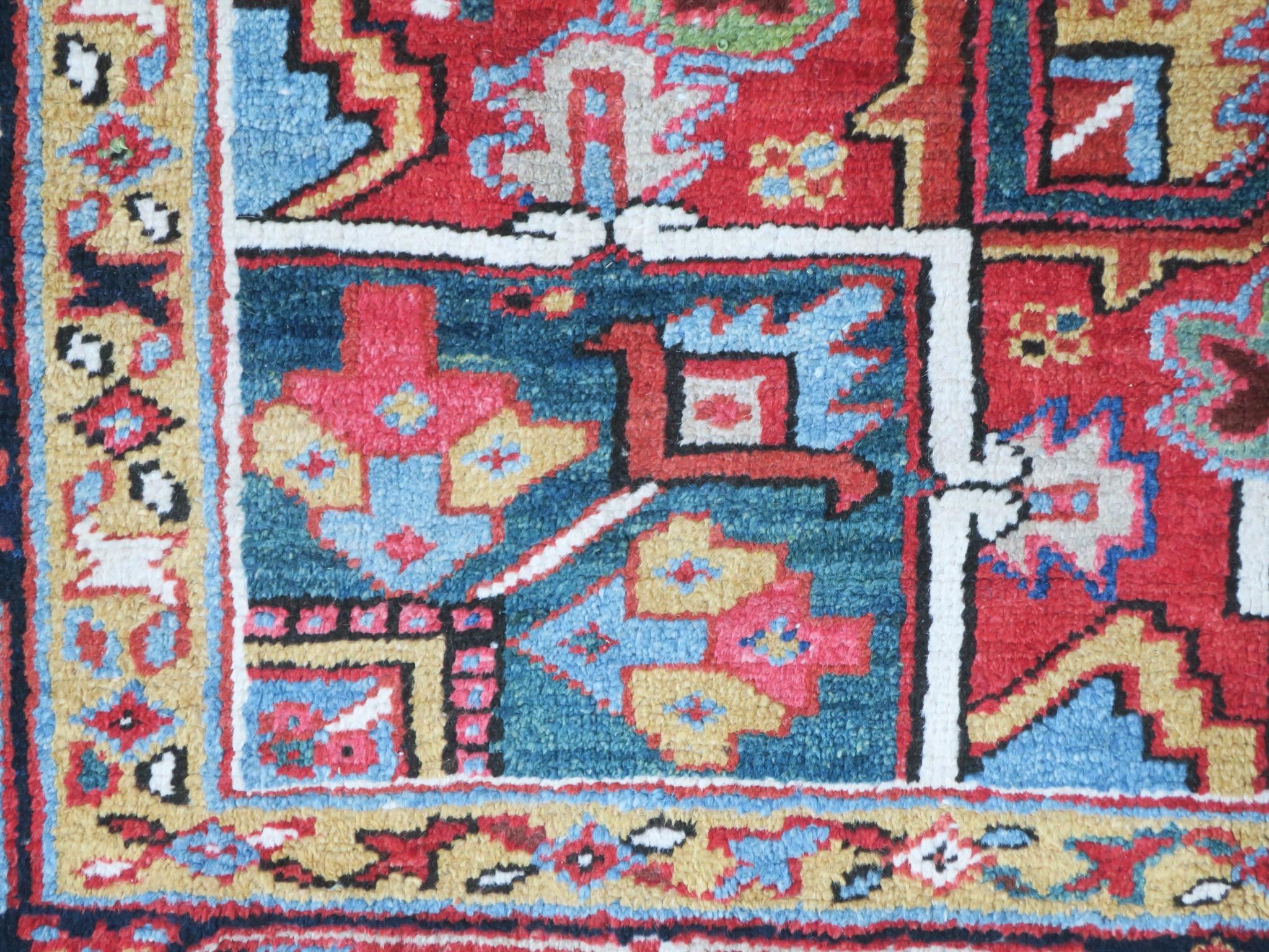 Antique Persian Heriz carpet dating from circa 1920 in very good condition, full pile with almost no signs of use, natural colors, angular design and attractive green corners, medallion with yellow lobes.