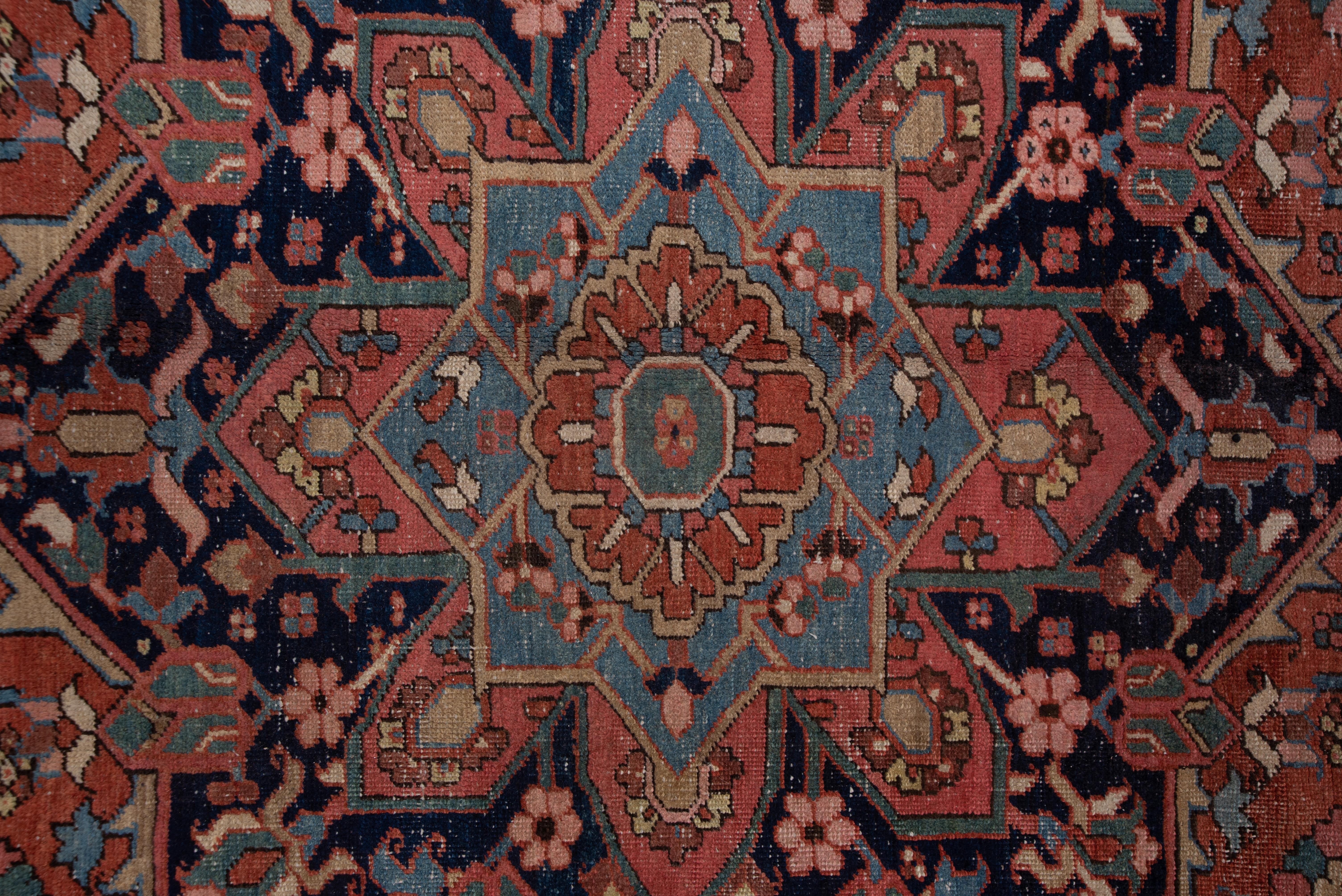 The tomato red field displays a navy octogramme medallion amidst semi-geometric flowers and leaves. The light blue corners show unusual scalloped edges while the navy border features a classic turtle palmette pattern.