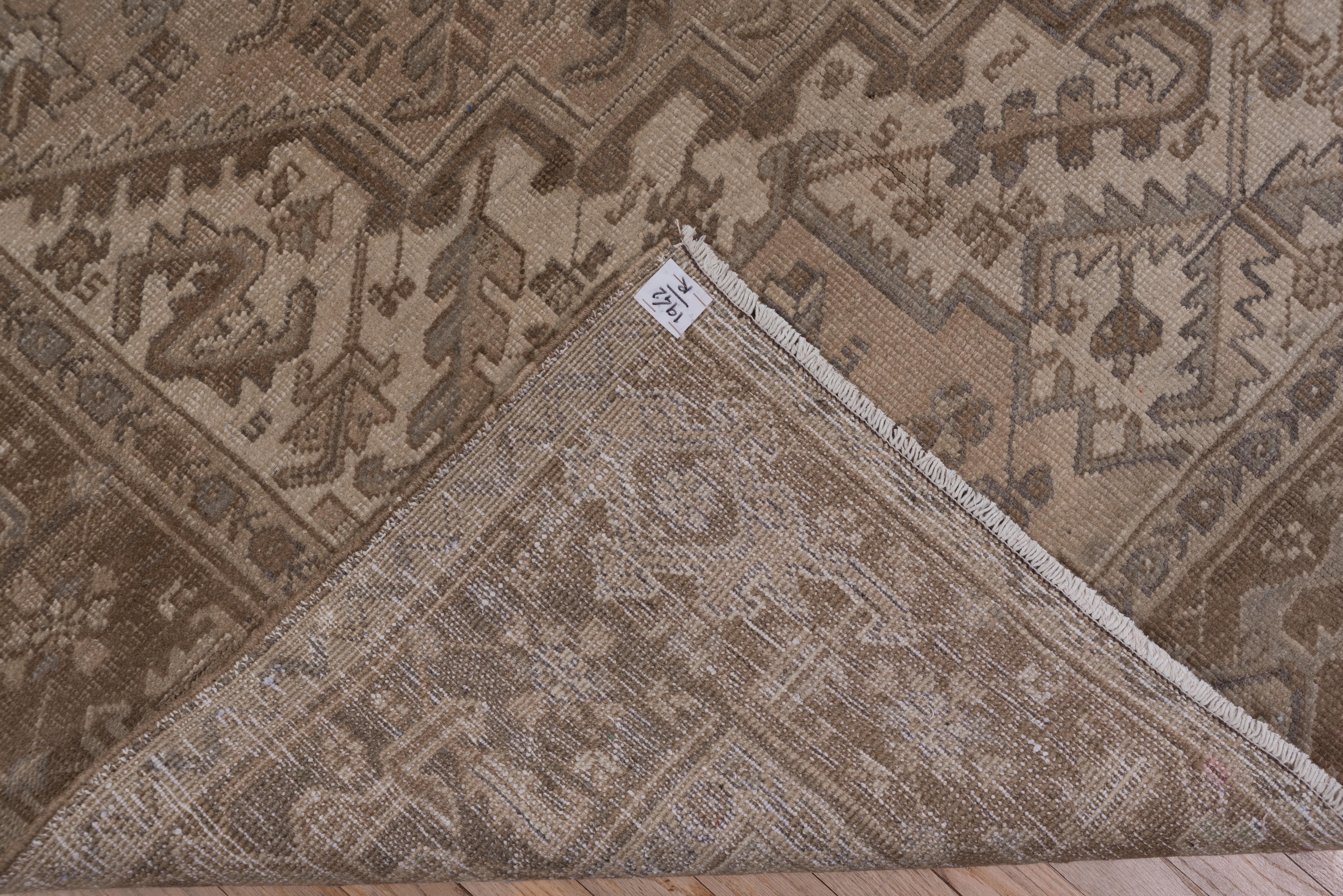 This rather mellow-toned NW Persian village carpet has a tan field with a giant brown stepped octogramme medallion and ivory joined spandrels. The decoration includes bent and S-contorted leaves. The light brown border displays a skeletal turtle