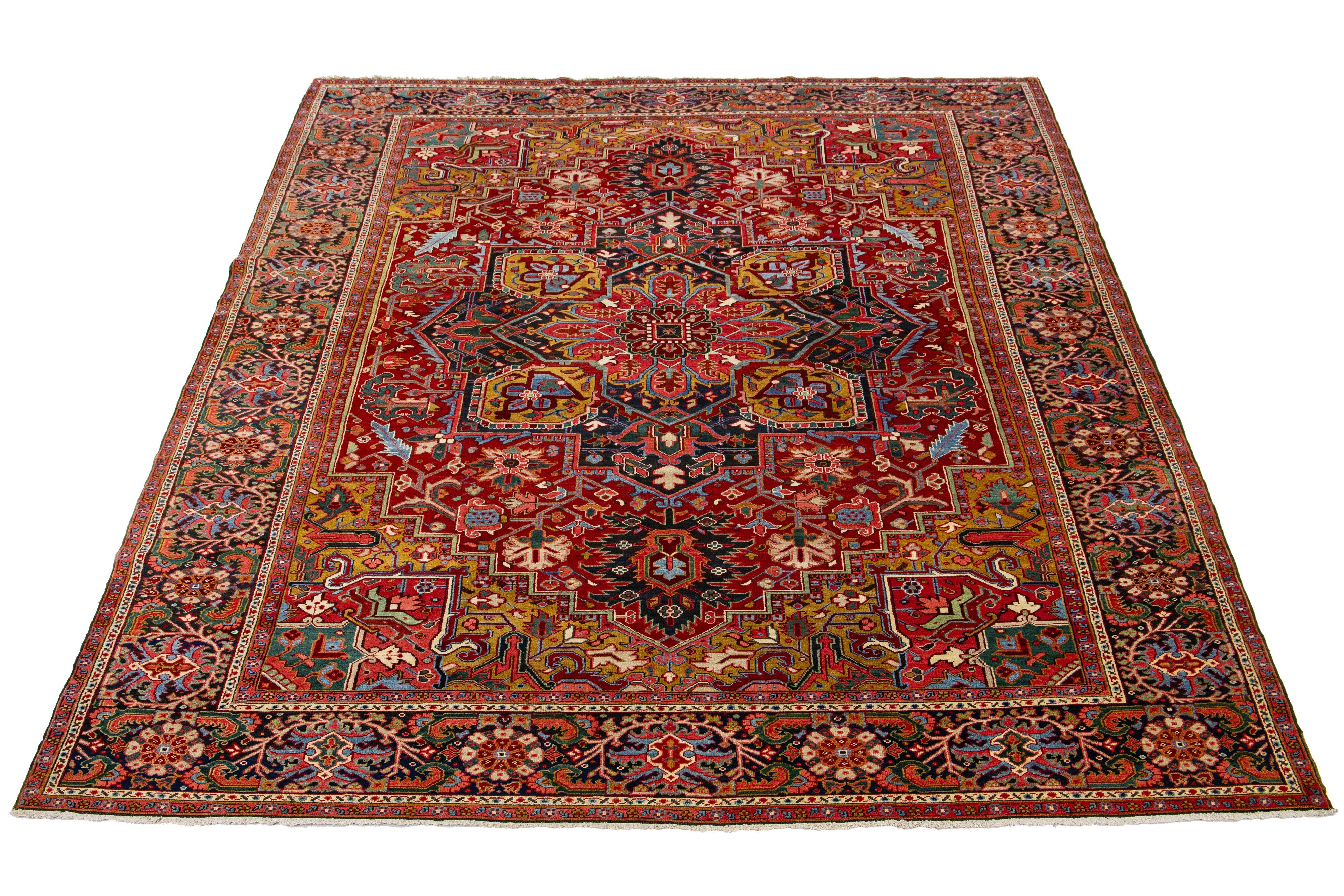 This beautiful antique Heriz hand-knotted wool rug features a red field. The Persian rug highlights a center medallion design with yellow, green, pink, and blue accents.

This rug measures 10' 4