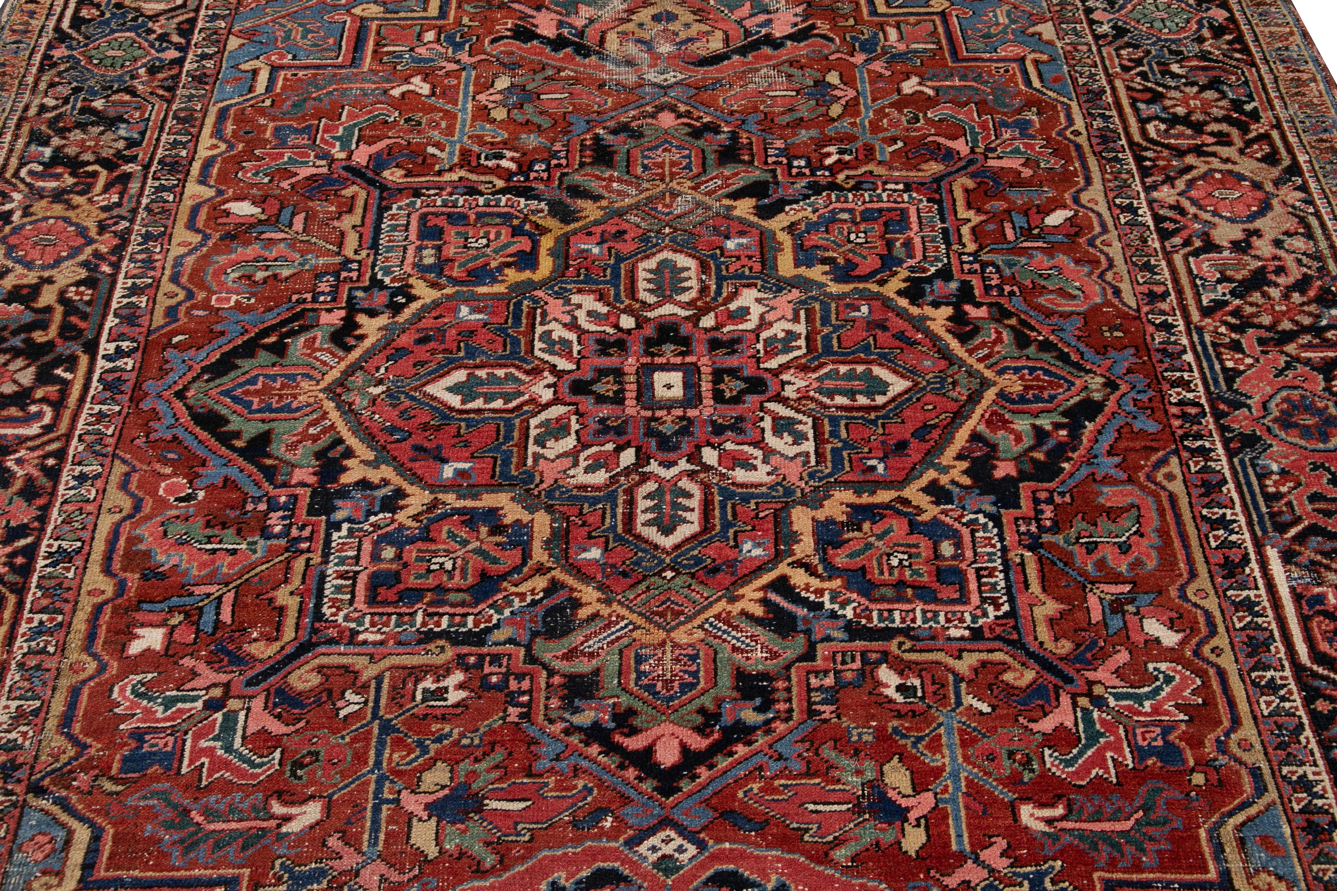 Beautiful antique Persian Heriz hand knotted wool rug with rust and blue field. This Heriz rug has a navy-blue frame and multi-color accents in an all-over gorgeous geometric medallion floral design.

This rug measures: 7'3